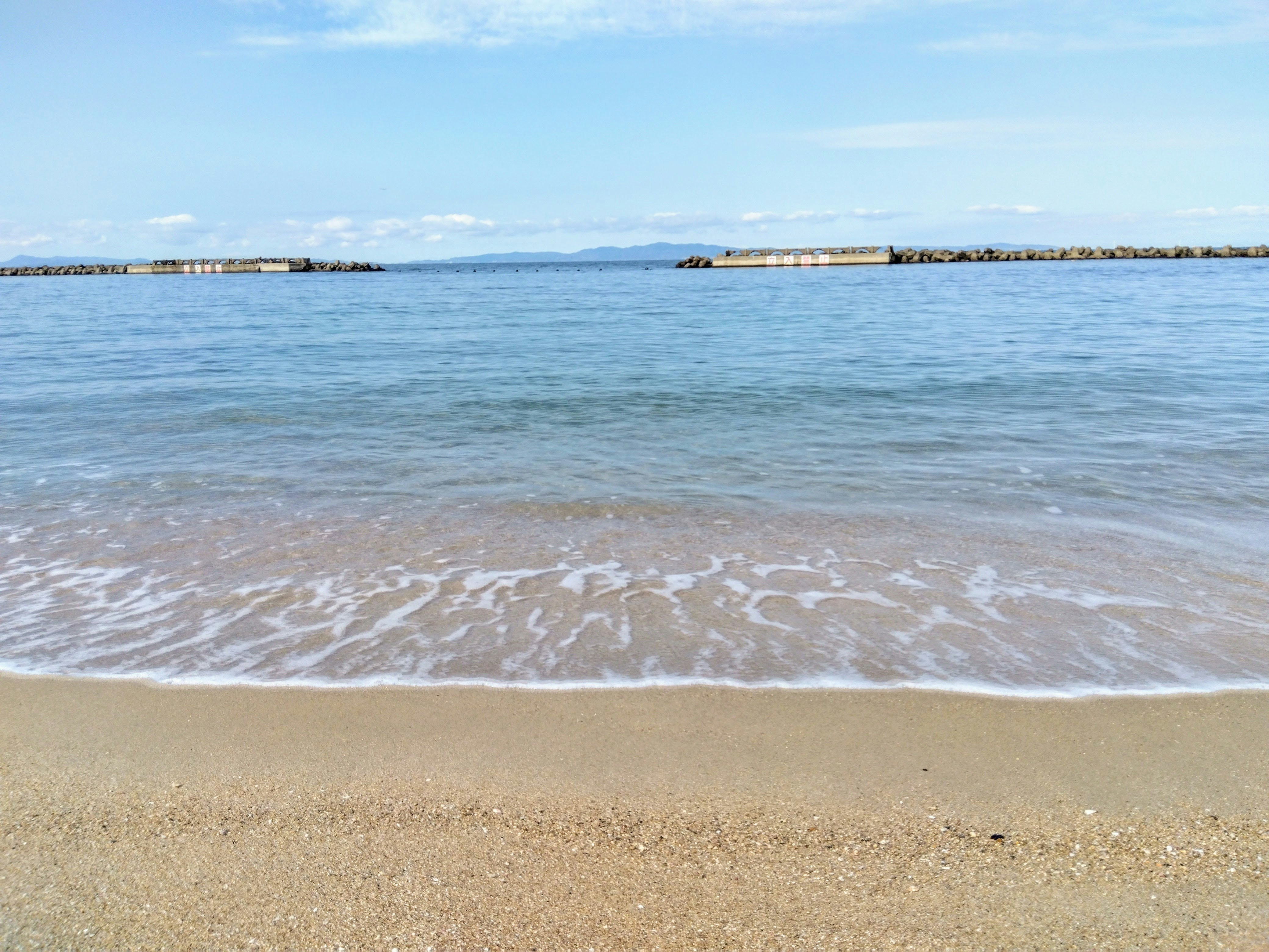 平靜海面與遠處防波堤的海灘海岸