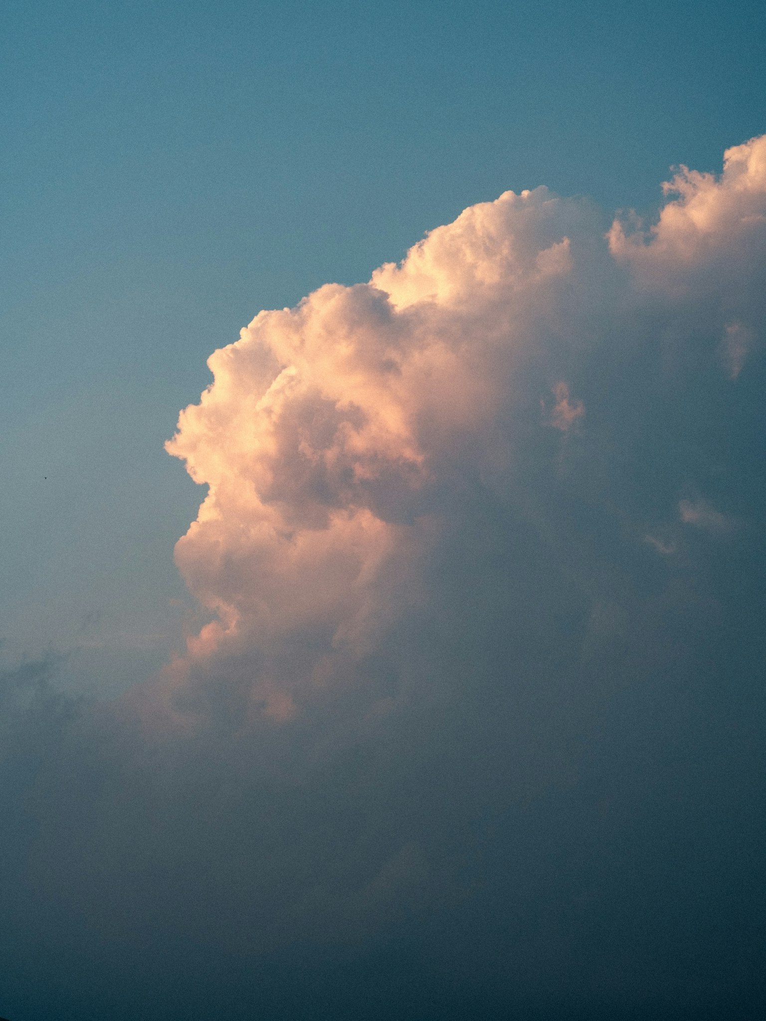 Partie d'un nuage illuminée par le coucher de soleil contre un ciel bleu