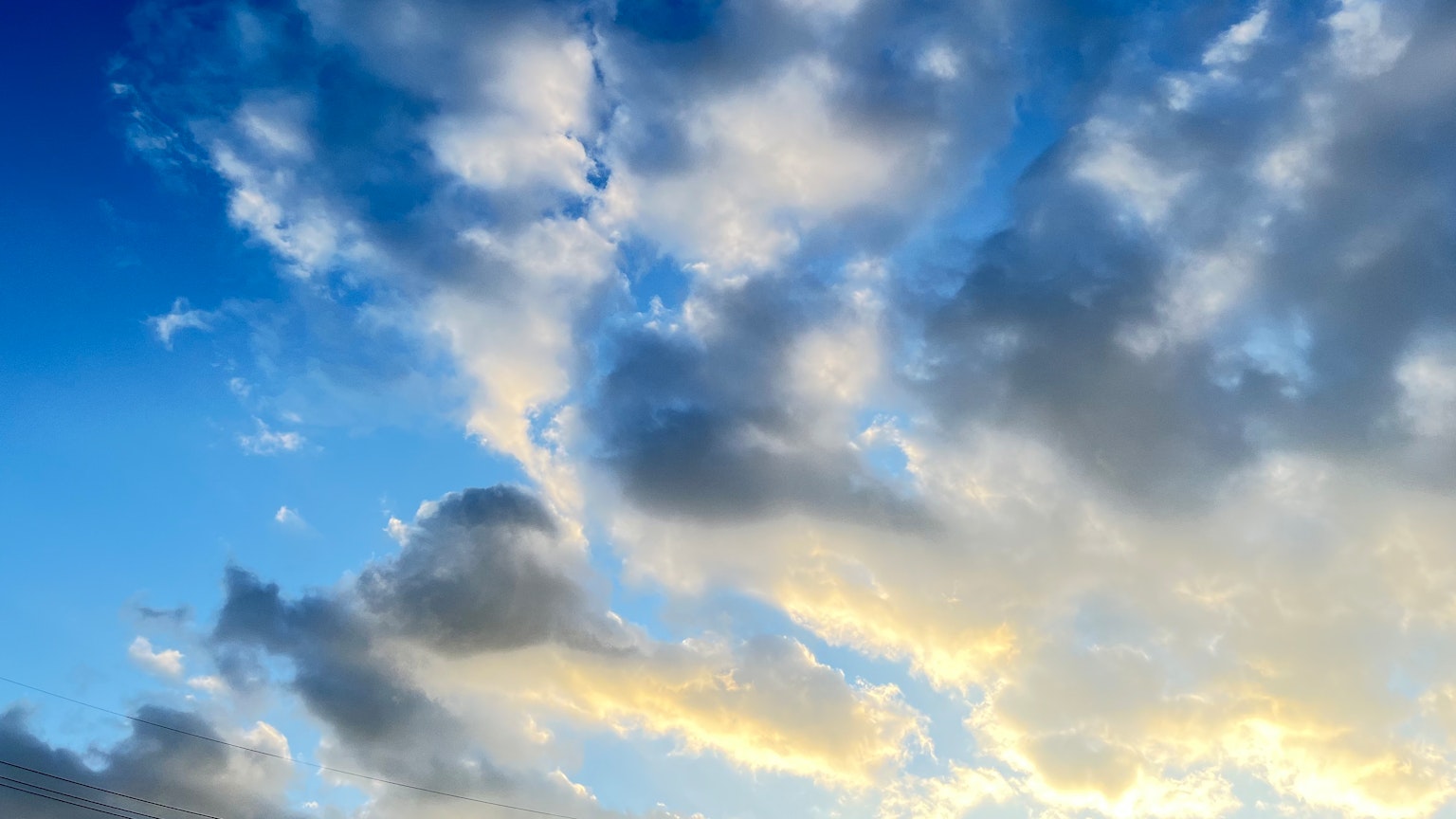 White clouds floating in a blue sky with orange light