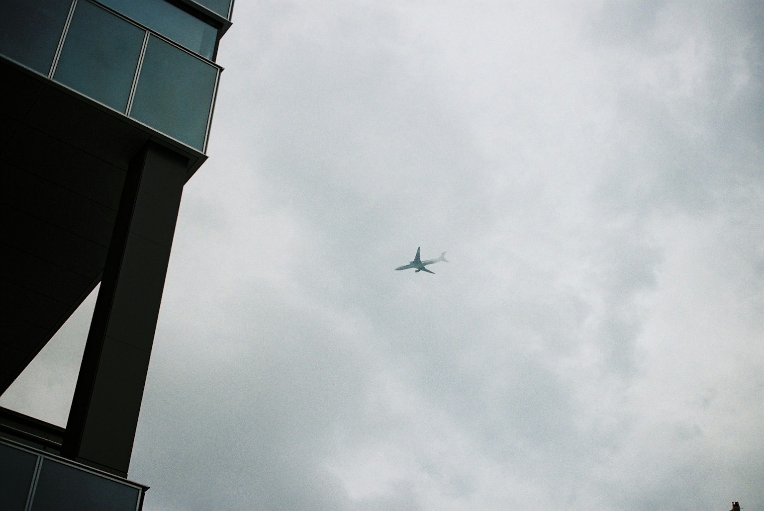 Ein Flugzeug fliegt durch bewölkten Himmel in der Nähe eines hohen Gebäudes