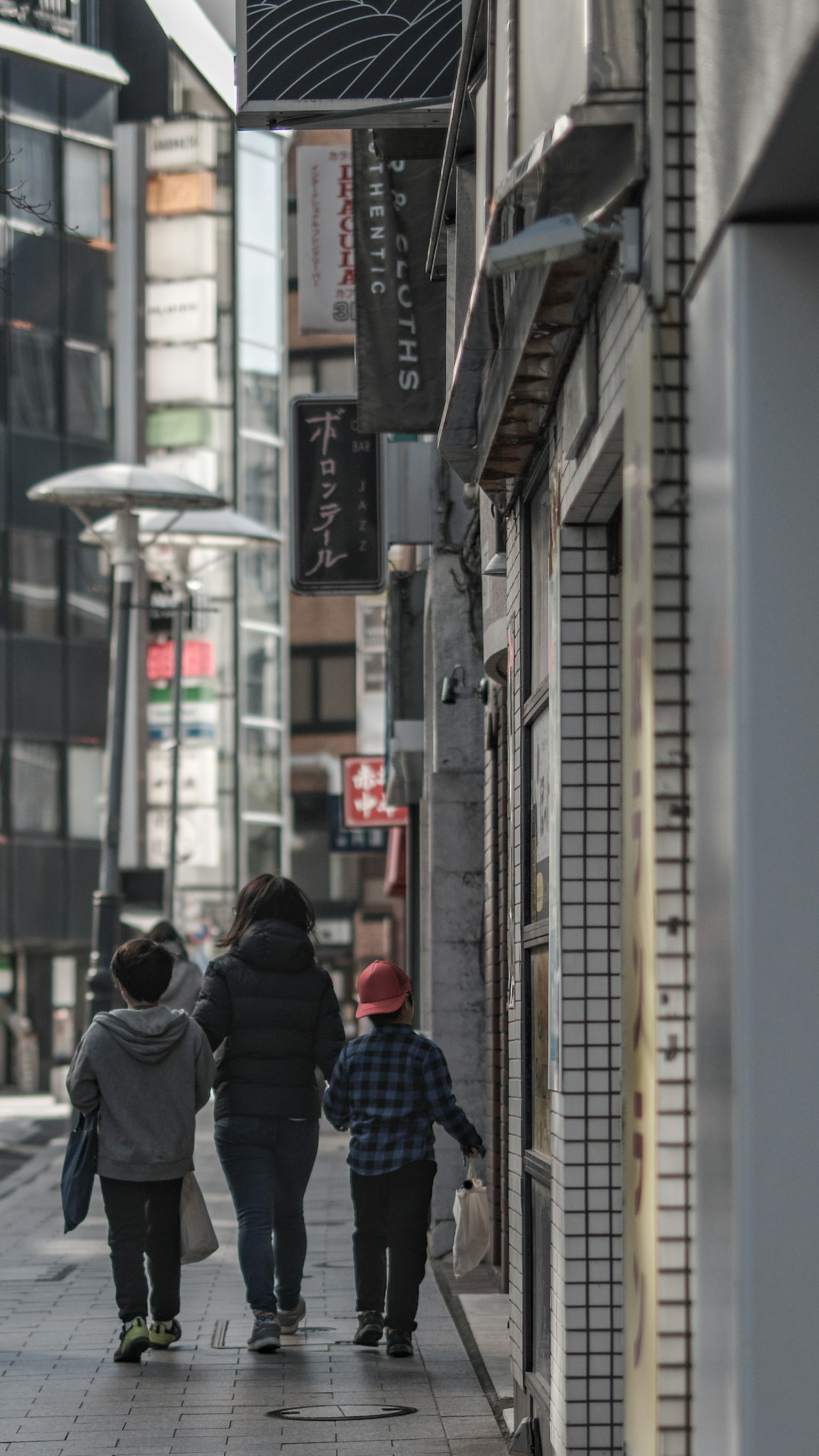 城市街道上走着的大人和孩子群体 现代建筑和标志在背景中