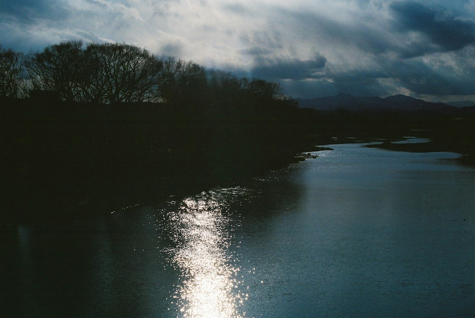 Ruhiger Fluss, der die Silhouette eines dunklen Himmels spiegelt