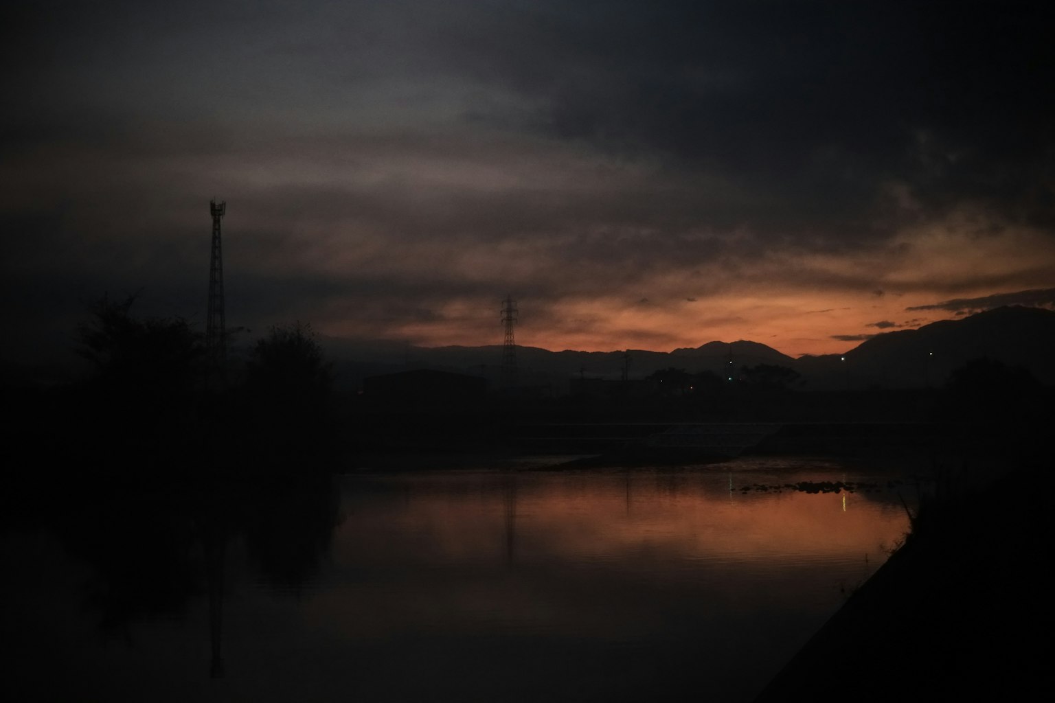 Ruhige Flusslandschaft in der Dämmerung mit dunklem Himmel