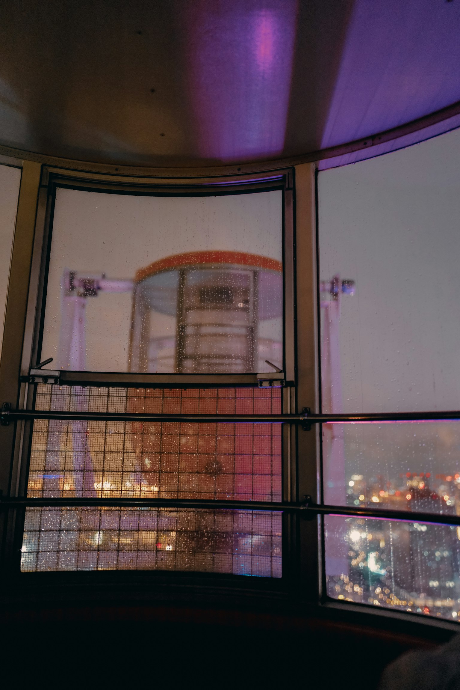 View from inside an observation deck showcasing city lights and colorful lighting at night
