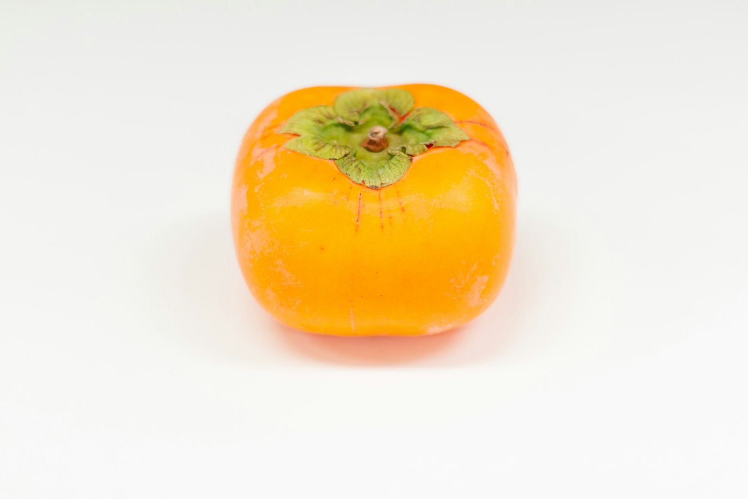 Eine leuchtend orangefarbene Persimone auf einem weißen Hintergrund
