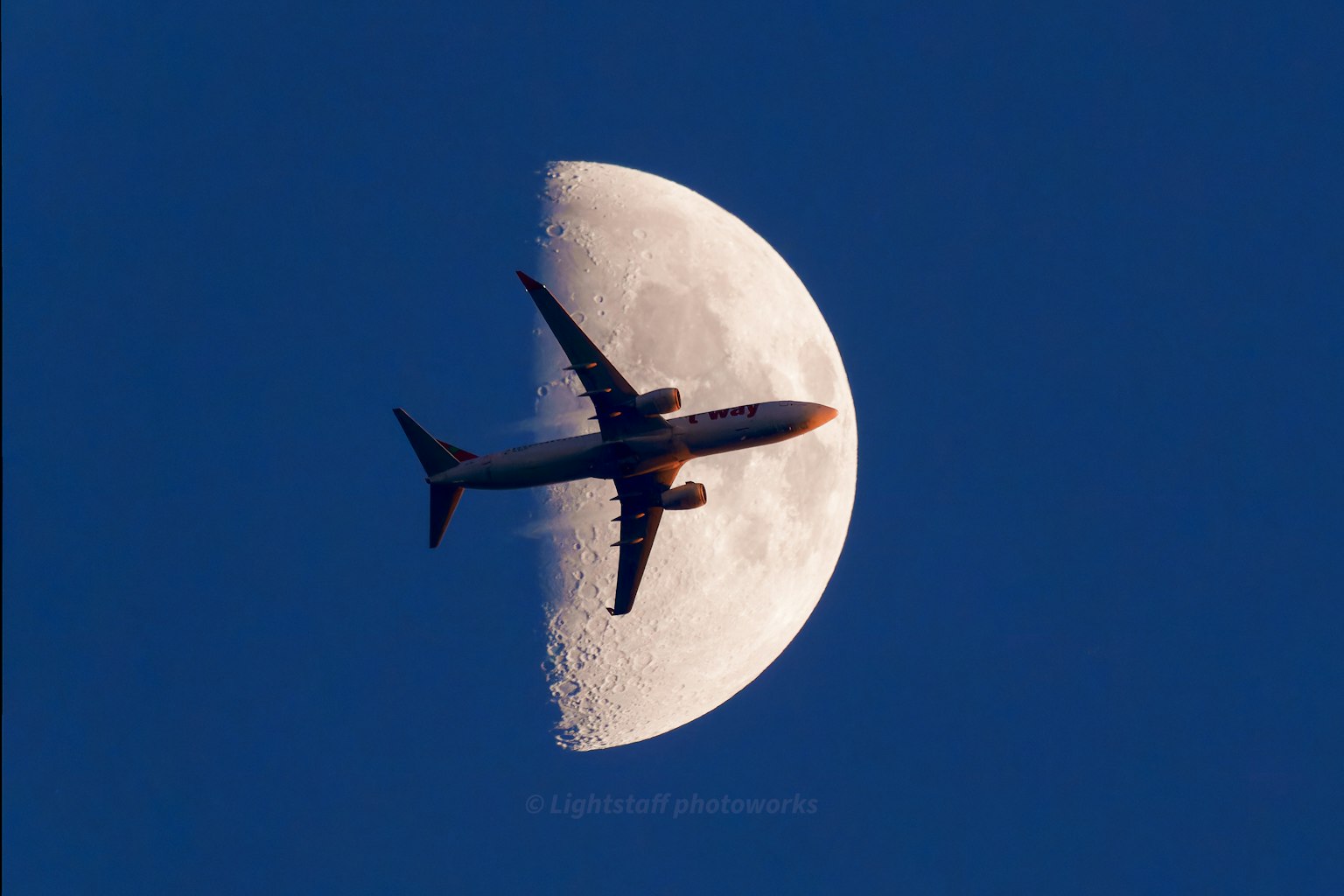 Ein Flugzeug, das vor dem Hintergrund eines Halbmondes fliegt