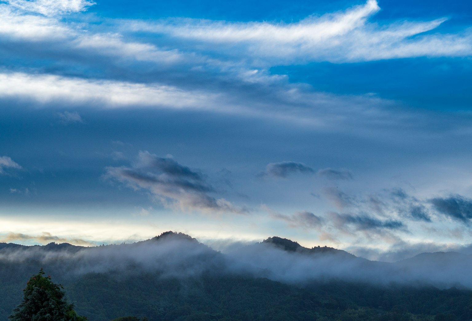 Vista panoramica di montagne avvolte nelle nuvole sotto un cielo blu