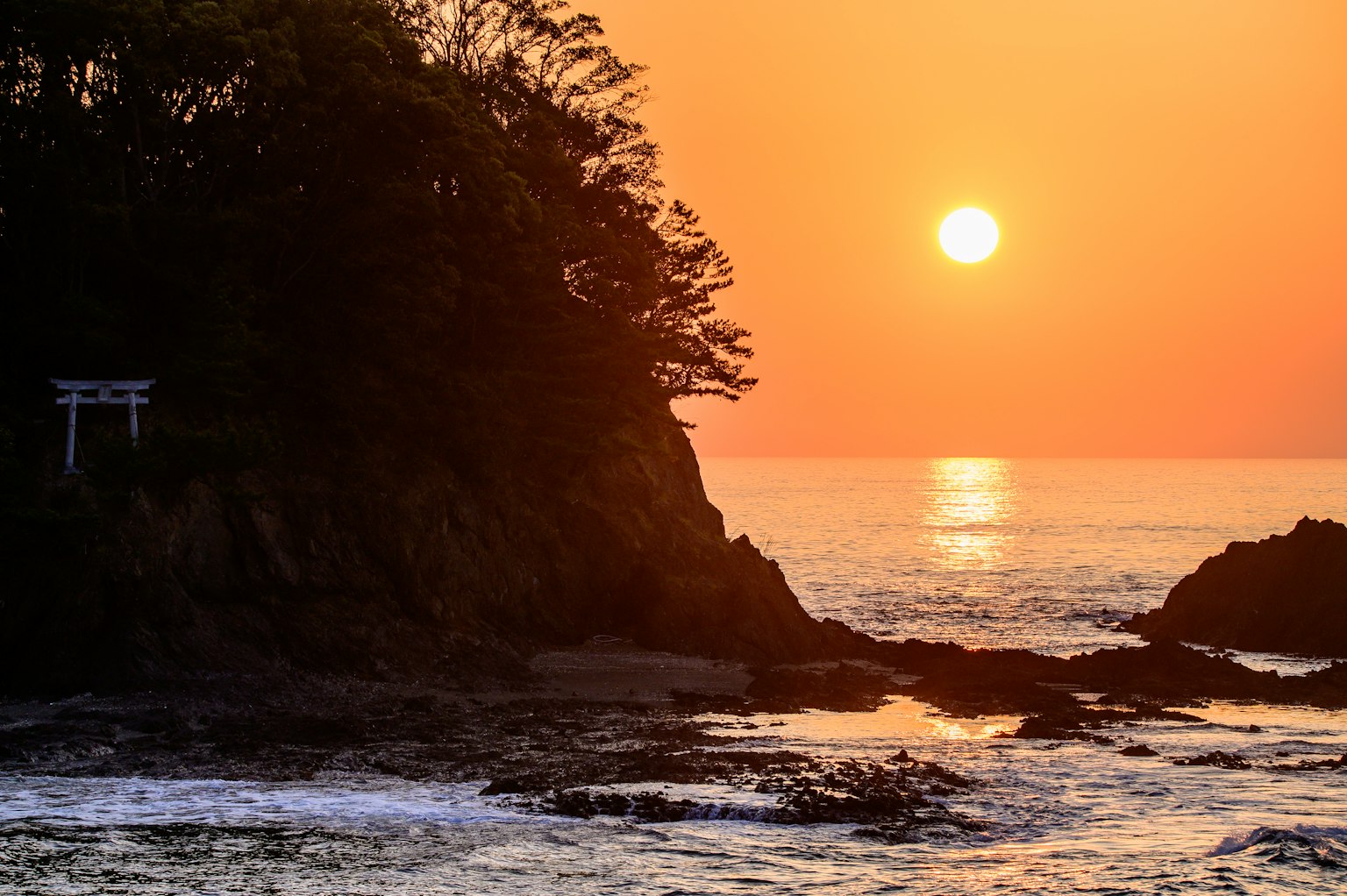 Bellissimo tramonto sull'oceano con un torii sulle rocce