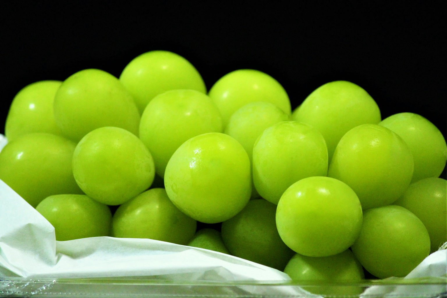 Un grappolo di uva verde accumulato su un tessuto bianco