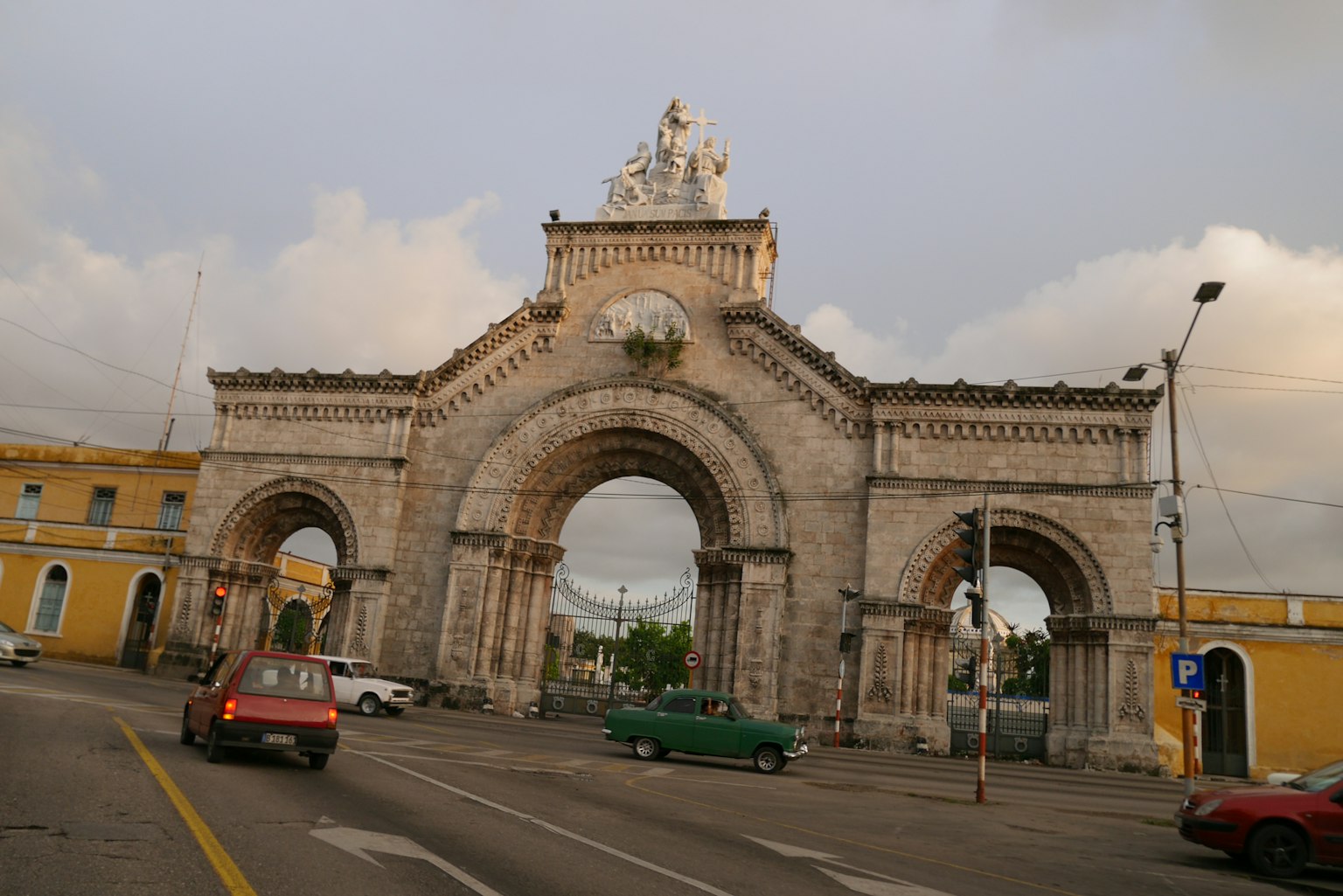 Arco storico in una scena cittadina con auto in transito e edifici circostanti