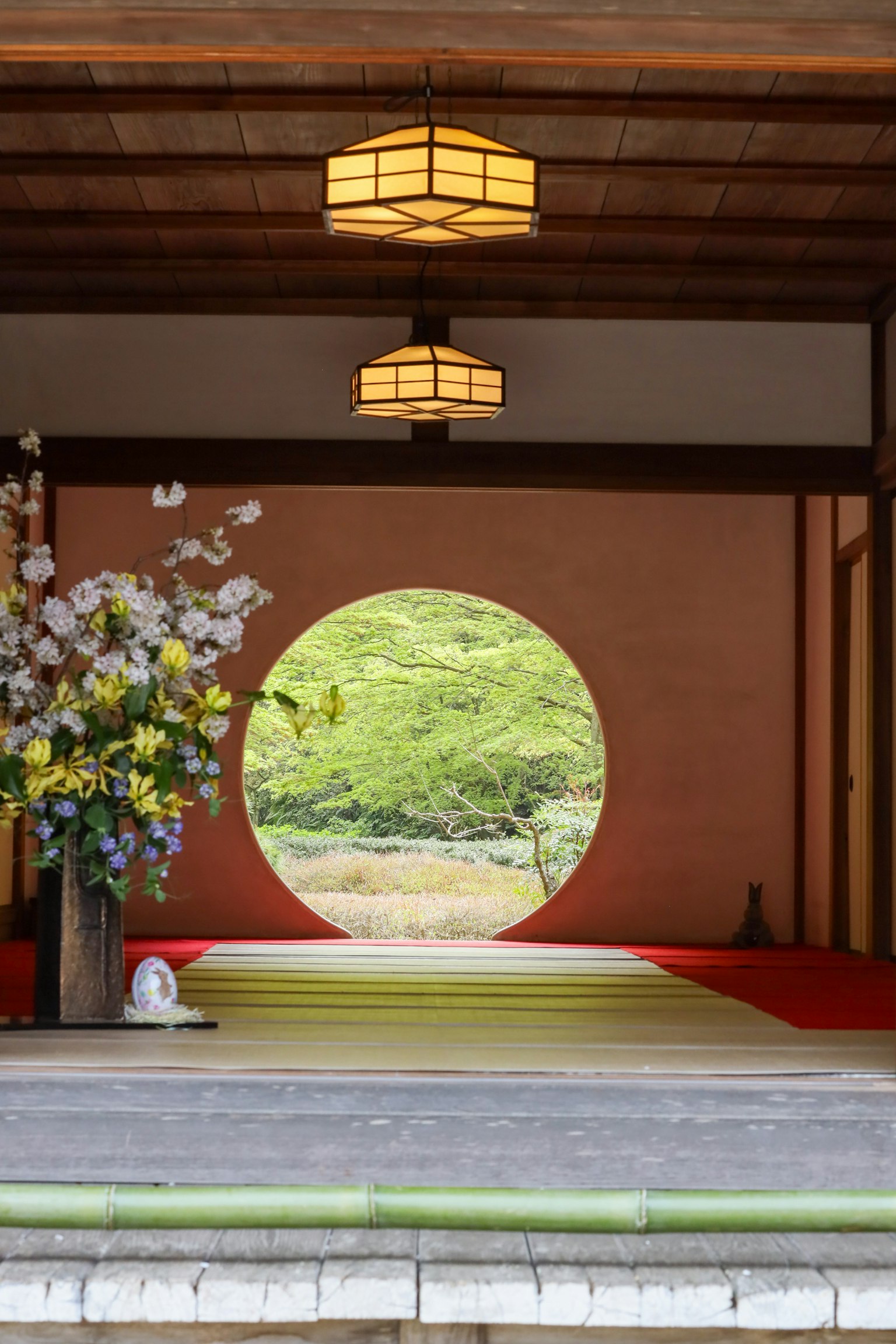 Vue intérieure avec une fenêtre ronde et un paysage vert avec une composition florale