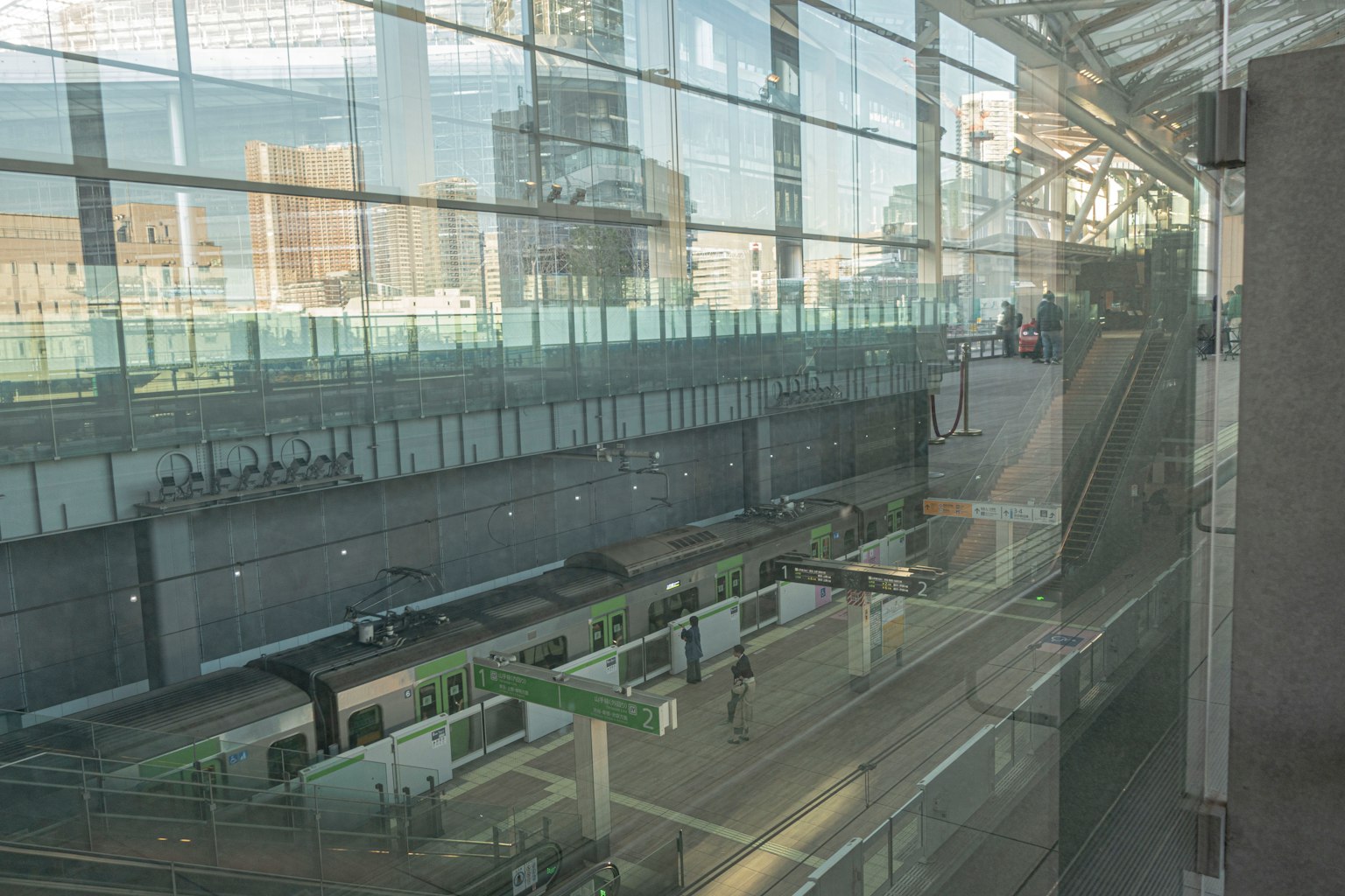 แพลตฟอร์มสถานีมองผ่านกระจกพร้อมรถไฟที่เข้าใกล้
