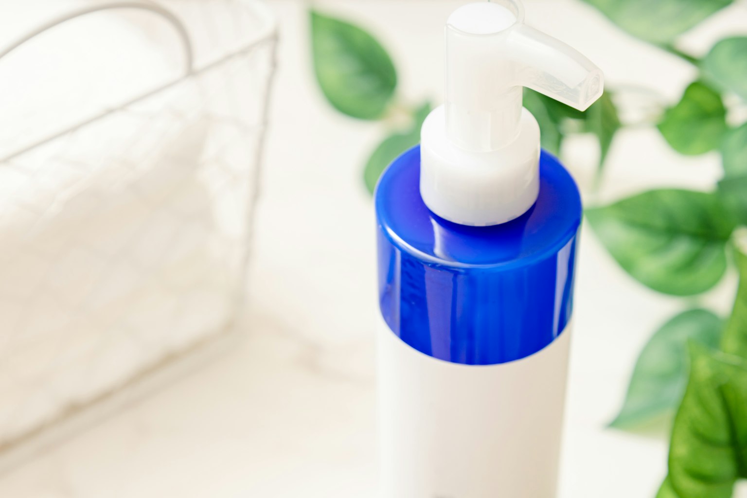 Botol pompa dengan tutup biru dan handuk di latar belakang