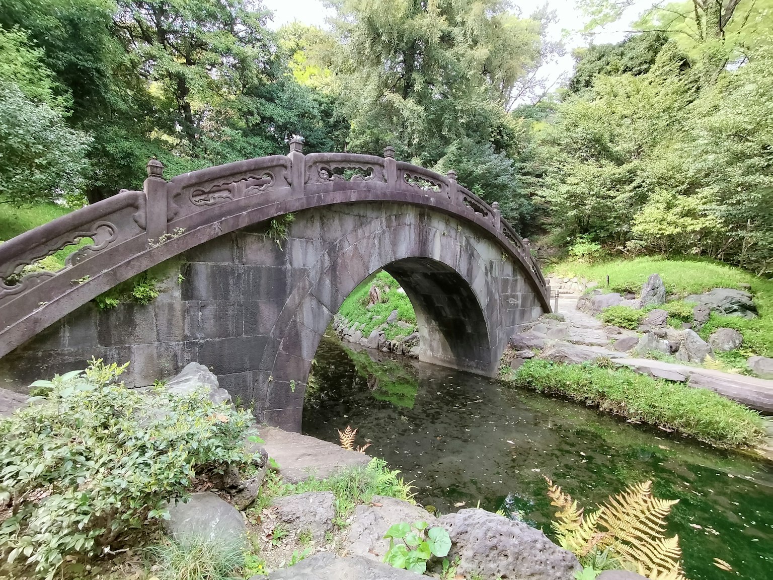 Eine ruhige Parkszenen mit einer schönen Steinbrücke, die über einen ruhigen Teich führt