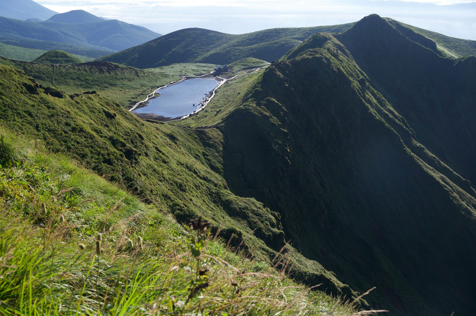 Vue pittoresque d'un lac tranquille entouré de collines vertes et de montagnes