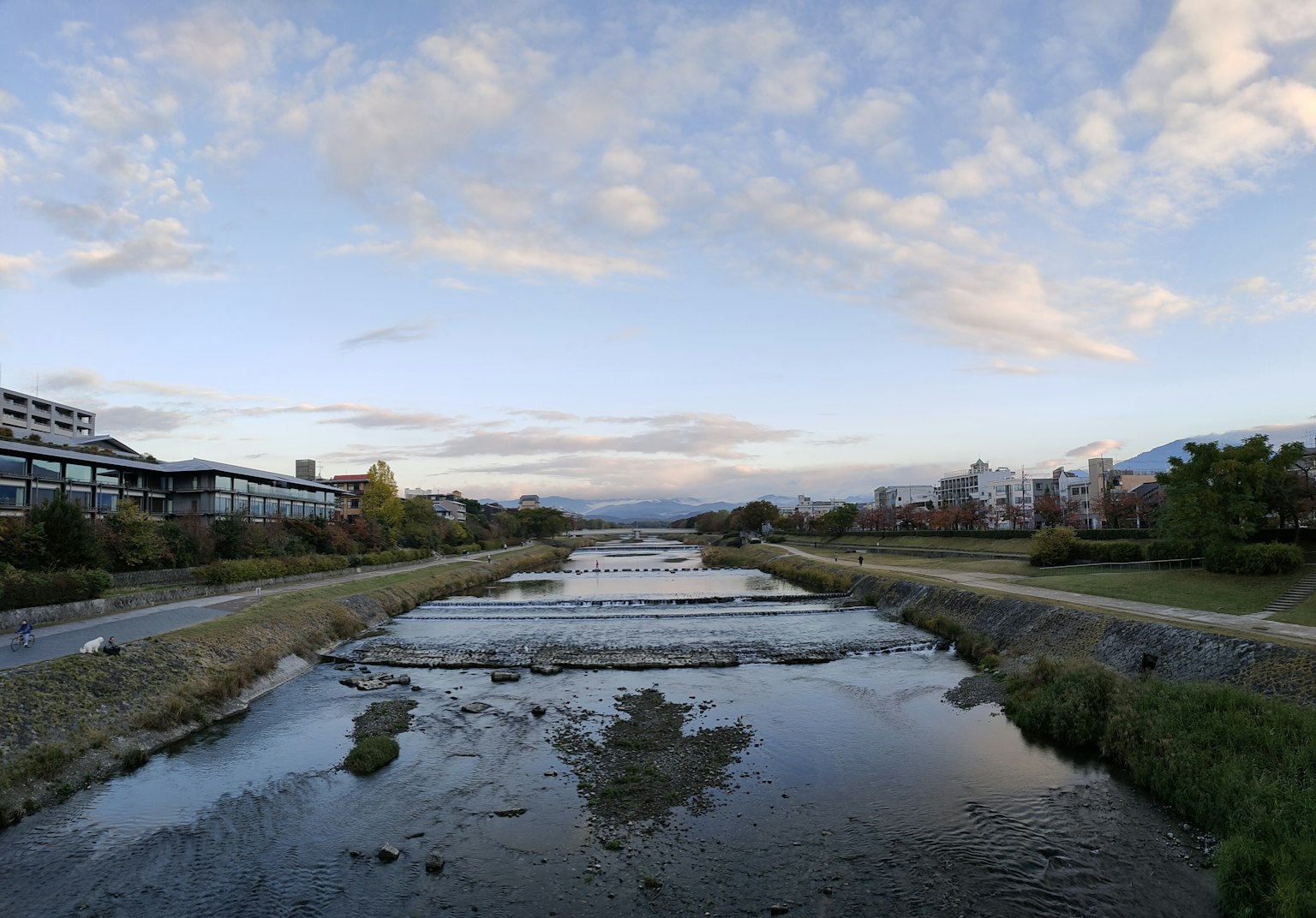 Scenic view of a river with buildings under a blue sky and clouds