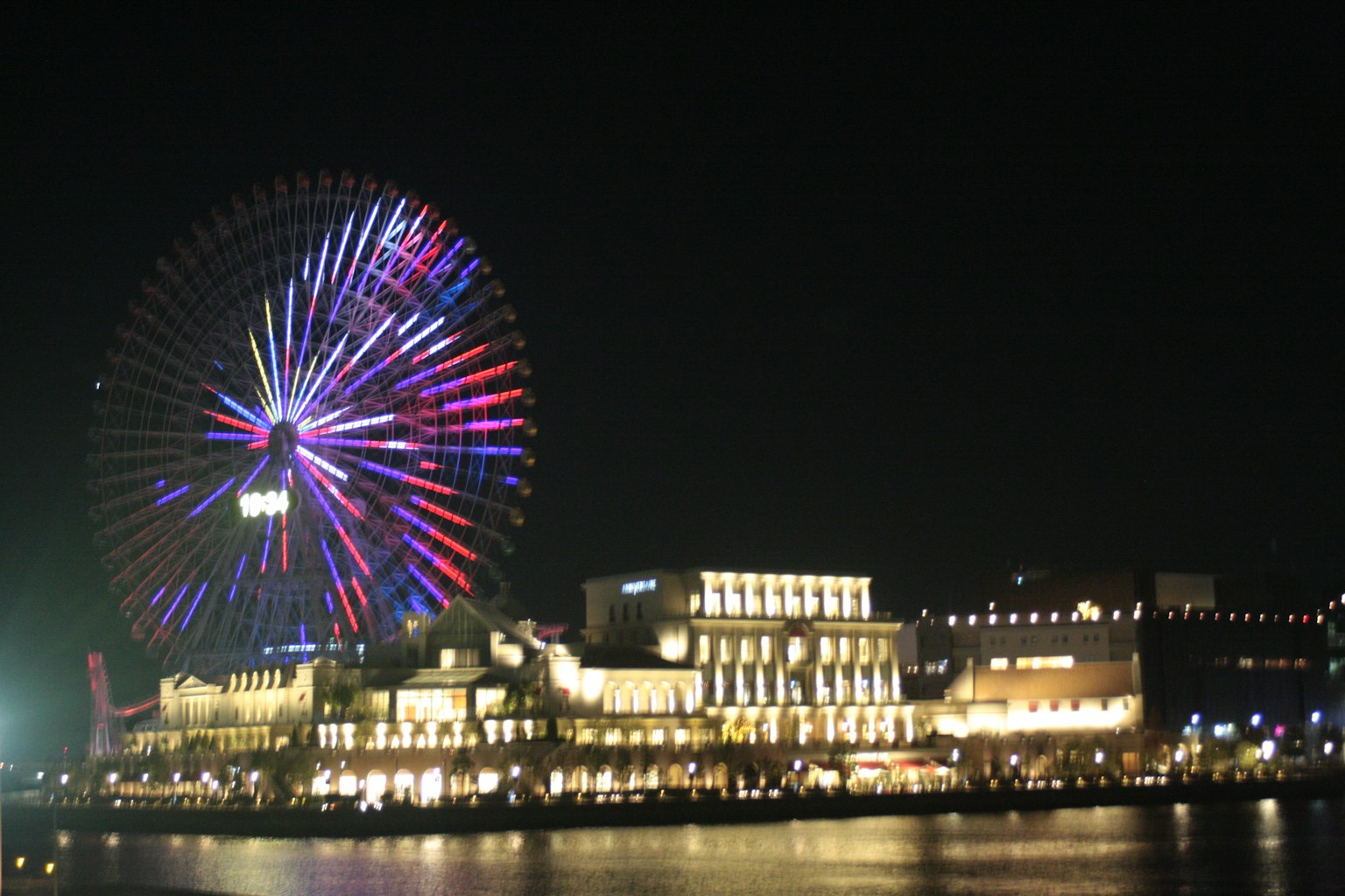 Vue nocturne d'une grande roue colorée et de bâtiments illuminés