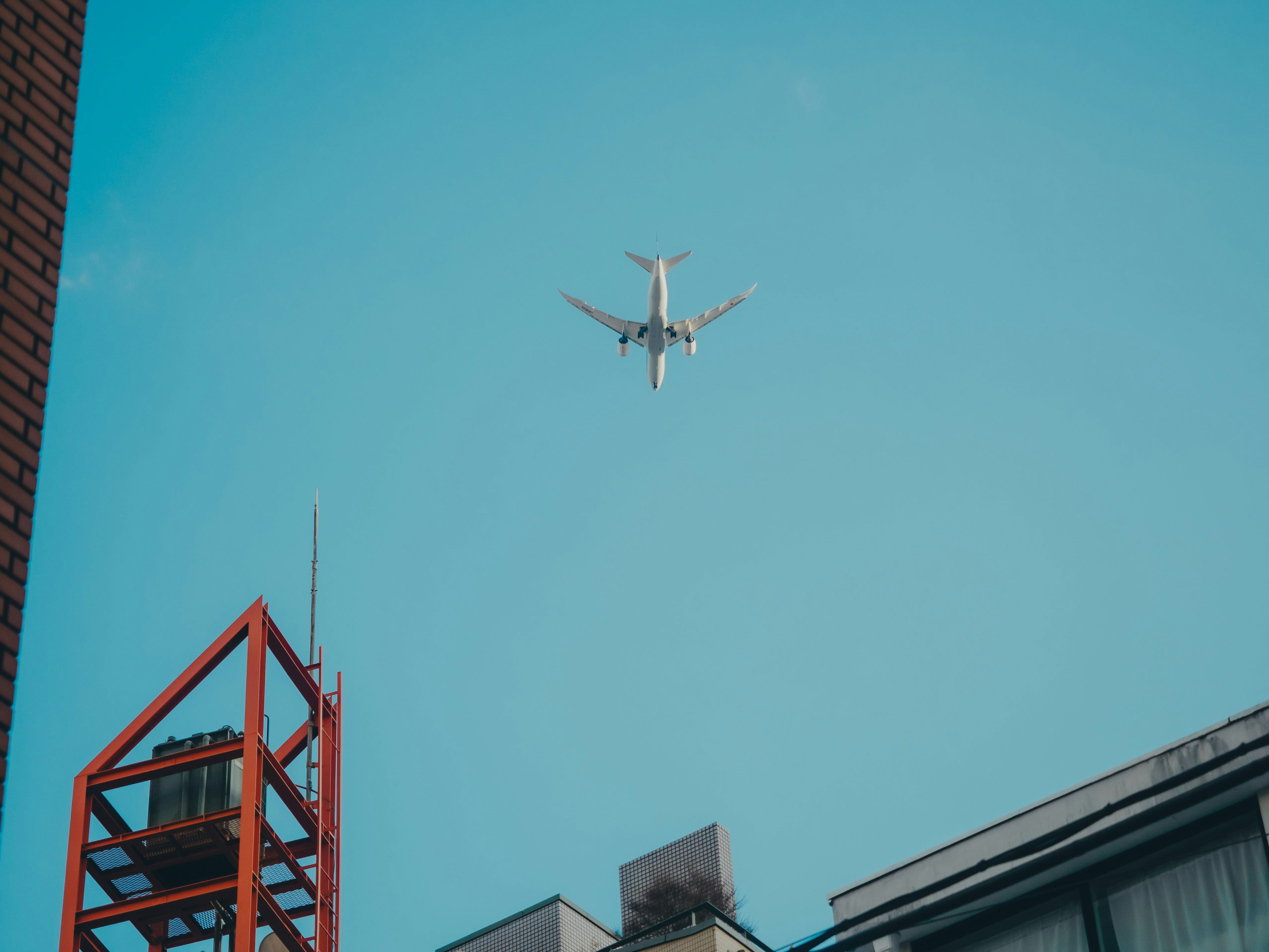 Passagierflugzeug fliegt über Gebäude vor klarem blauem Himmel