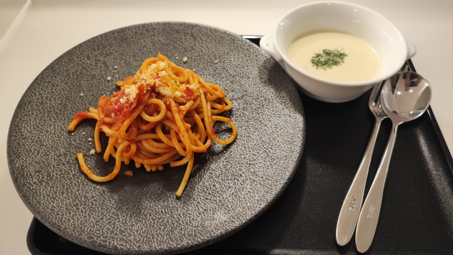 Sepiring spaghetti dengan mangkuk sup di samping
