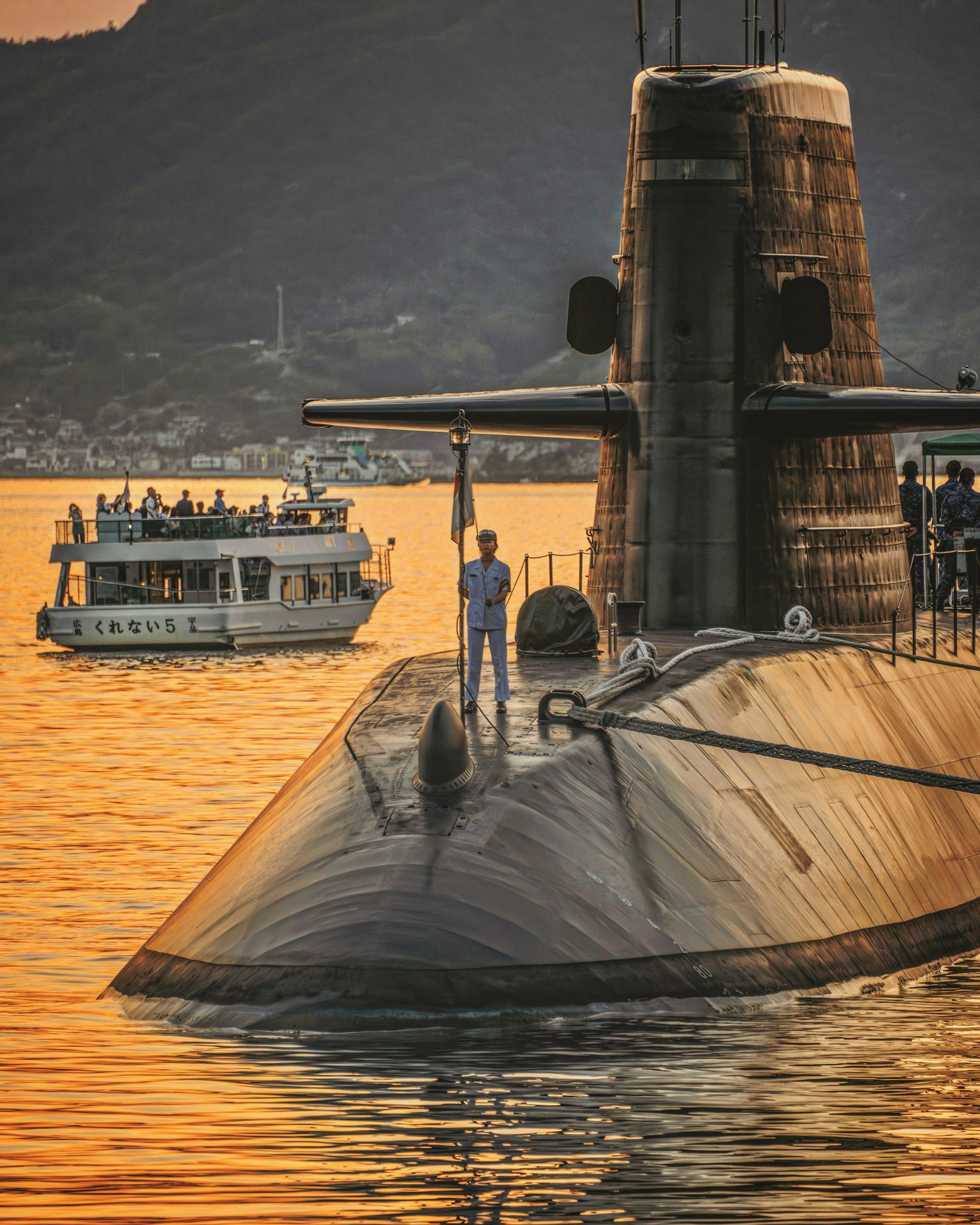 Submarine surfacing at sunset with a tourist boat nearby