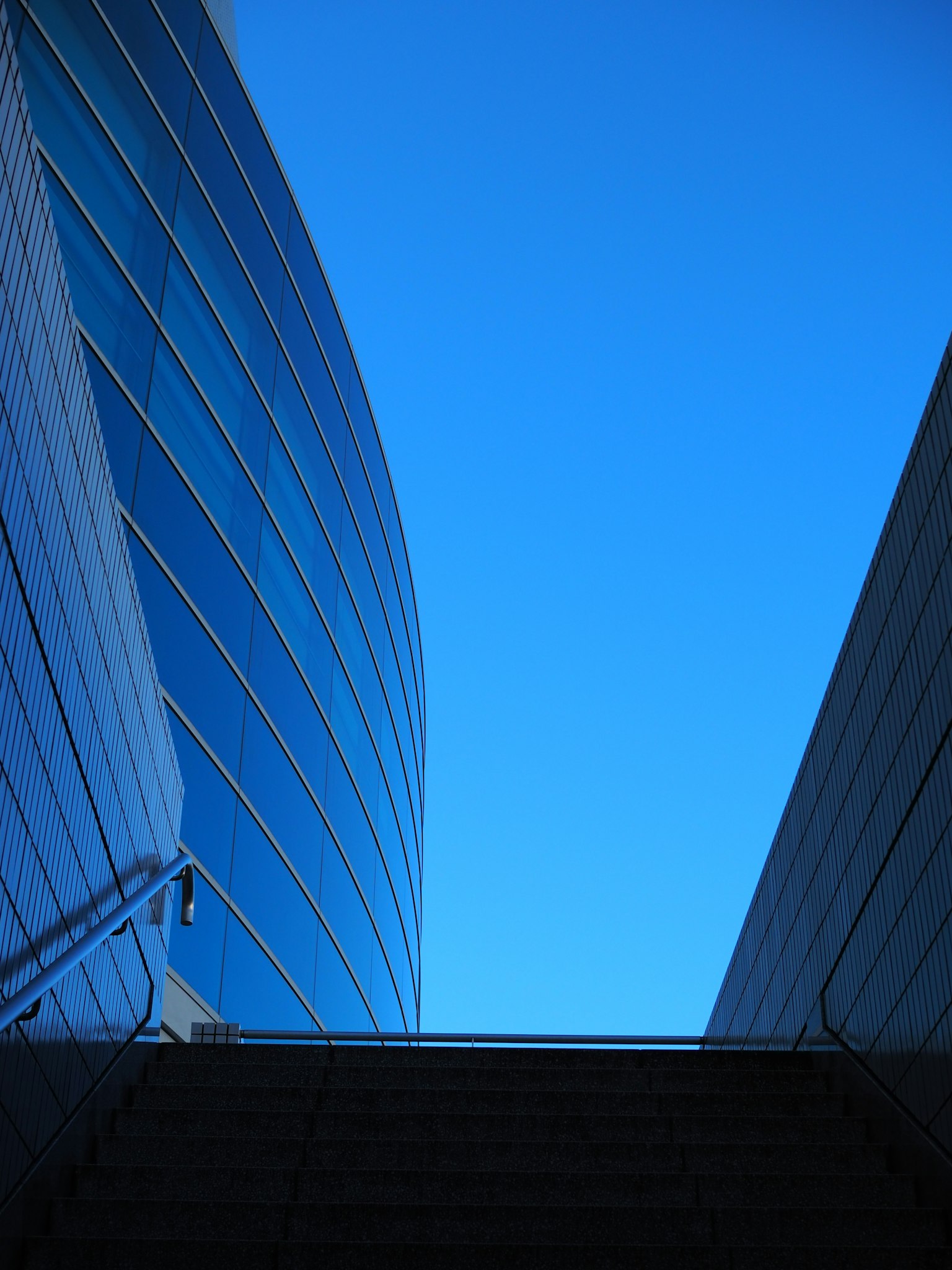 Modern building with curved glass façade under a clear blue sky