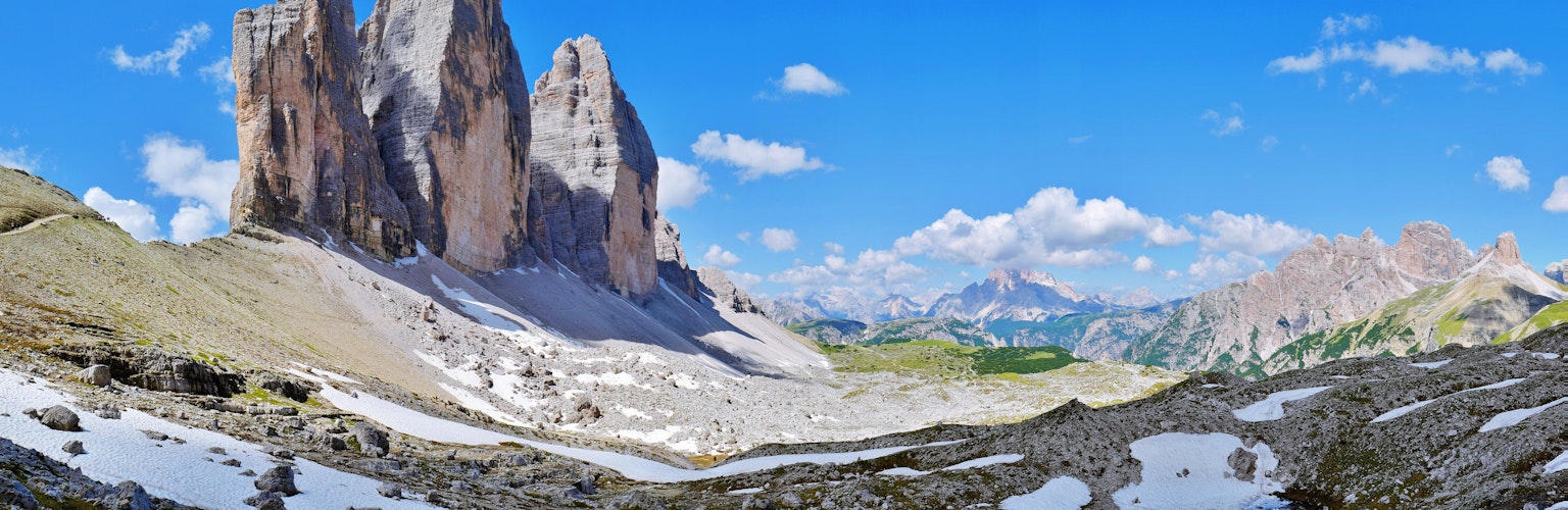 Atemberaubende Landschaft der Dolomiten mit blauem Himmel und weißen Wolken, schneebedeckten Gipfeln