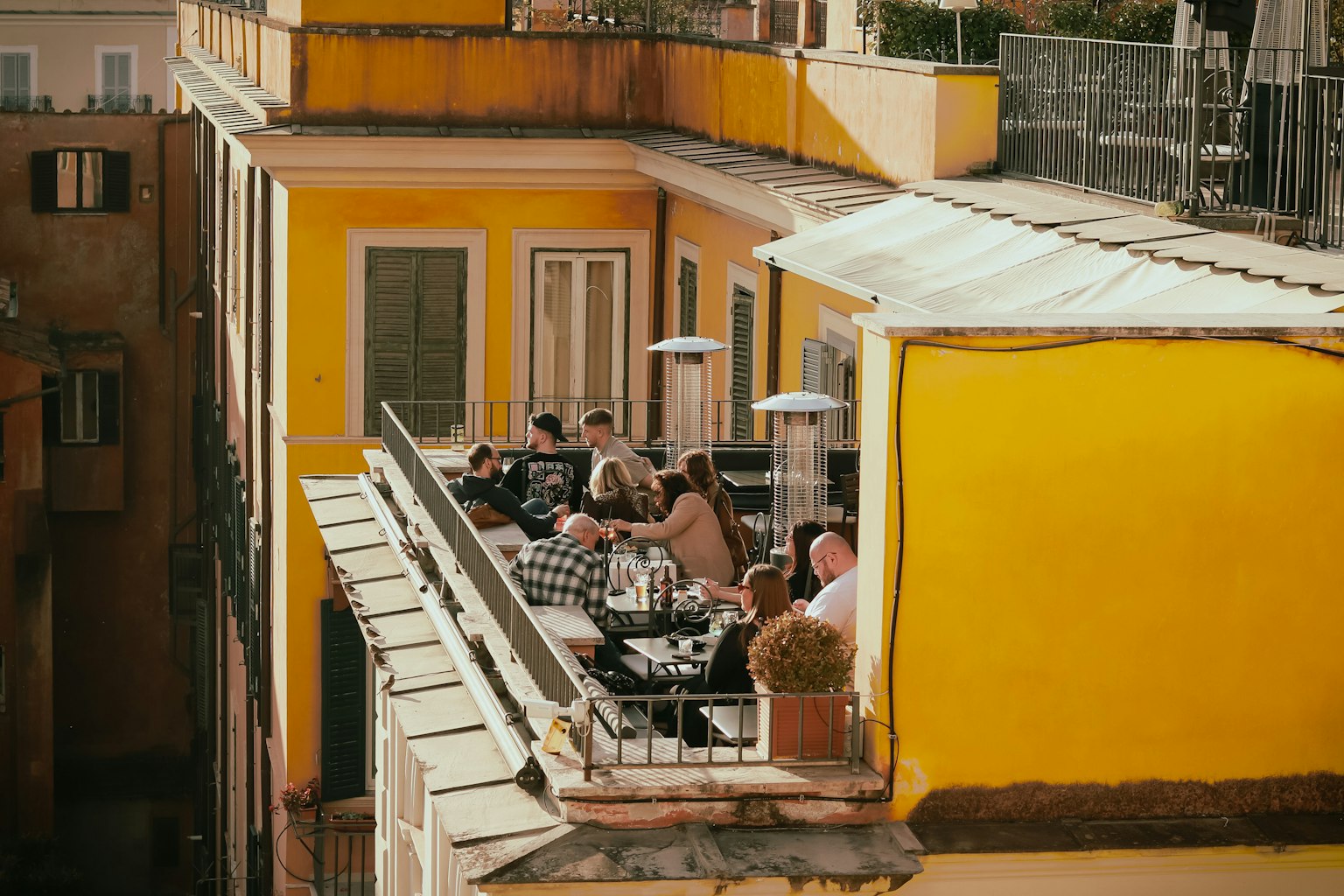 Menschen, die auf einem Balkon eines hellgelben Gebäudes essen