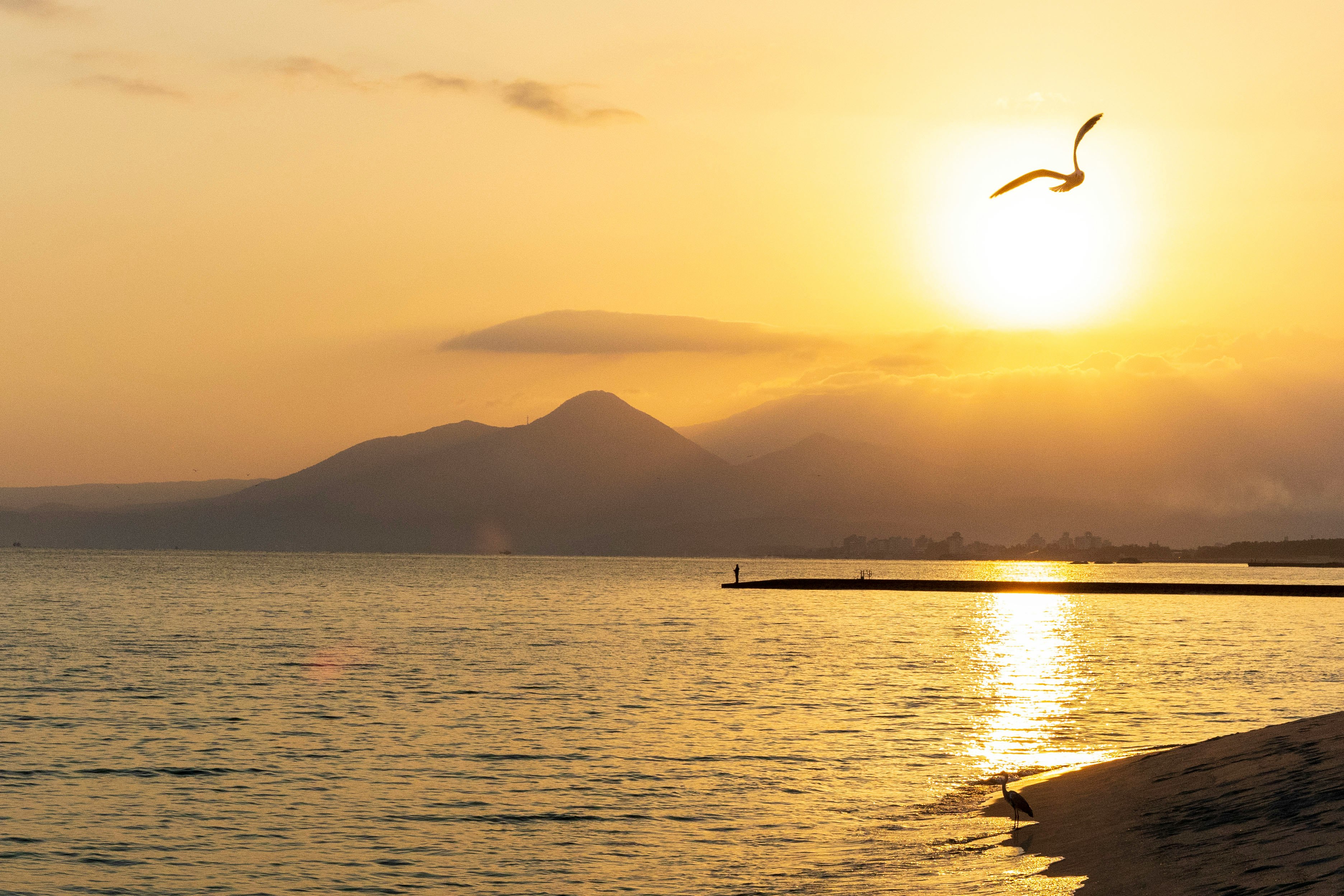 夕日の海辺と沖合の島影