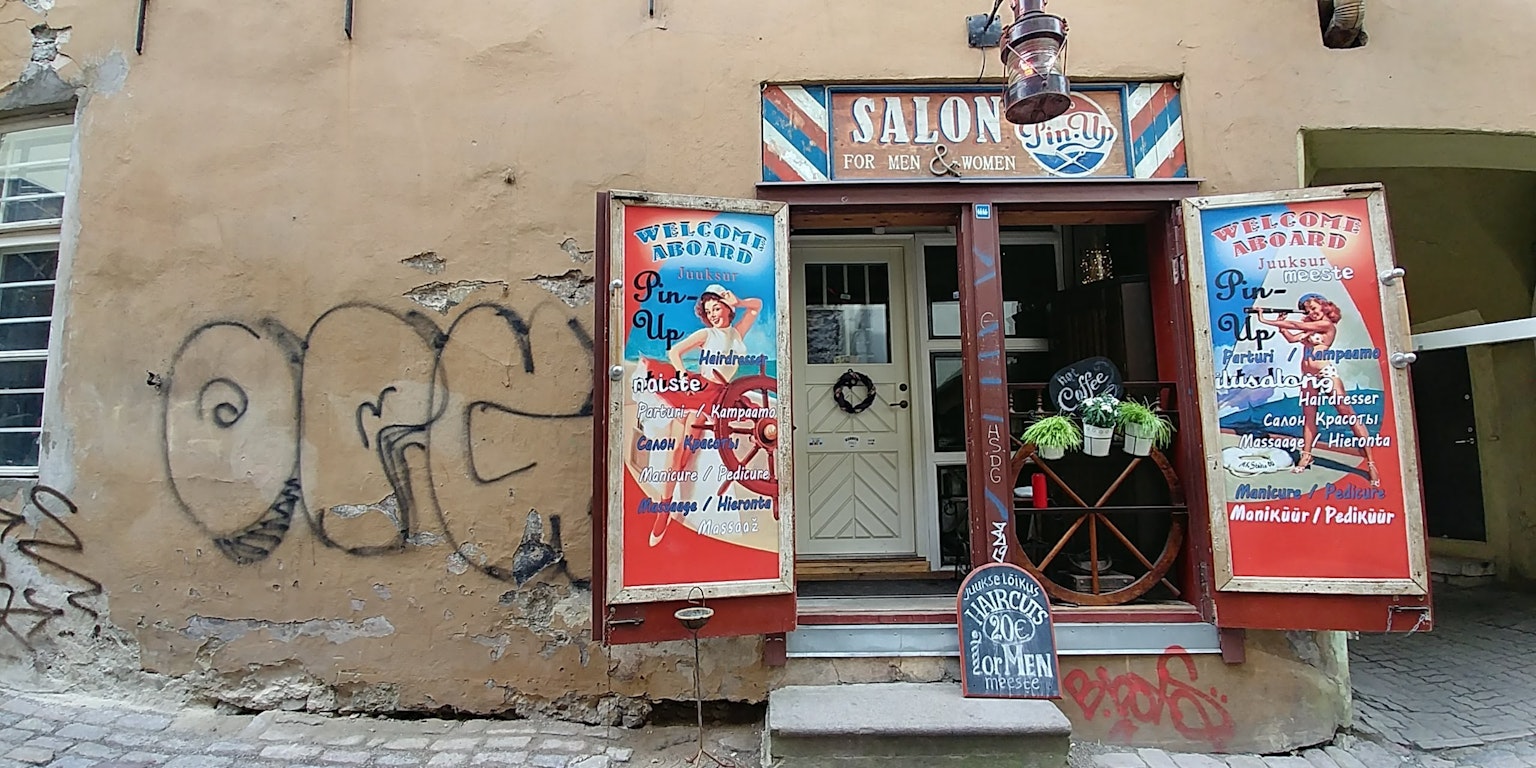 Exterior of a barbershop with colorful signage and doors featuring graffiti on the wall
