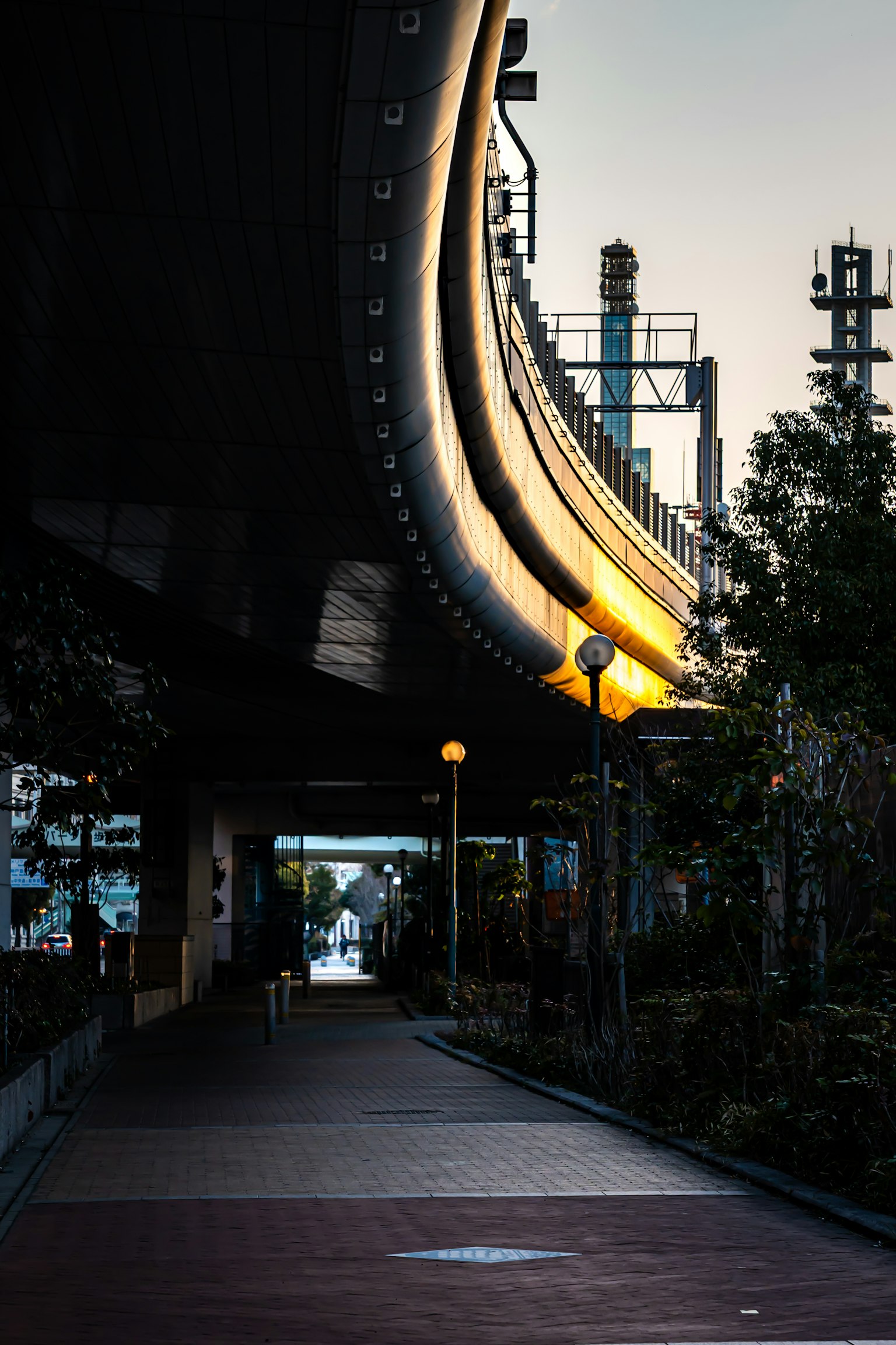 Scène urbaine sous un viaduc courbé avec des lampadaires et un fond industriel