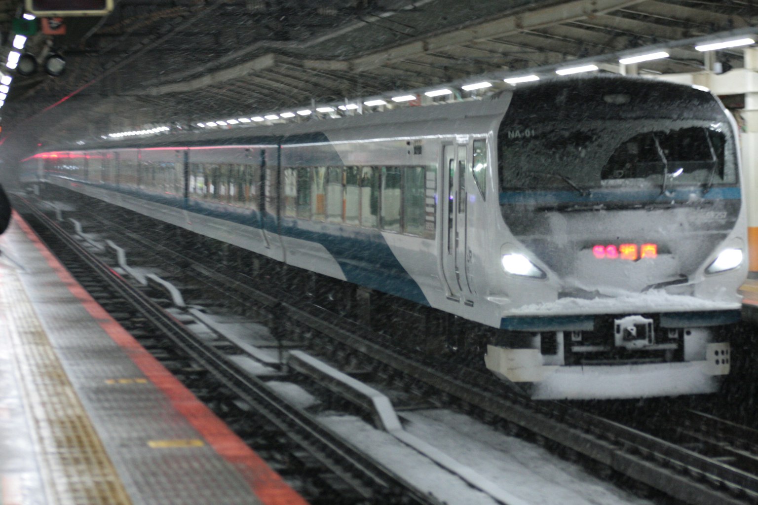 Treno che arriva a una stazione in condizioni di neve