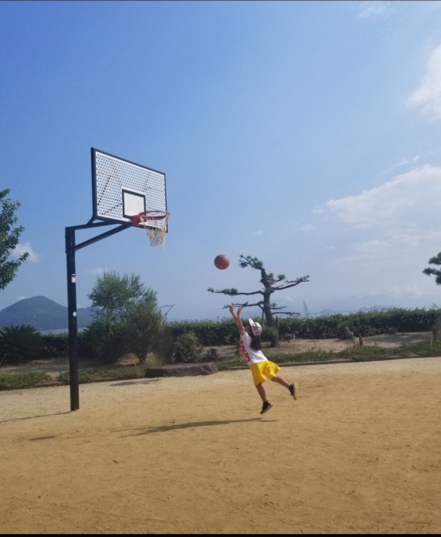 Un enfant qui shoote au basket sur un terrain de parc