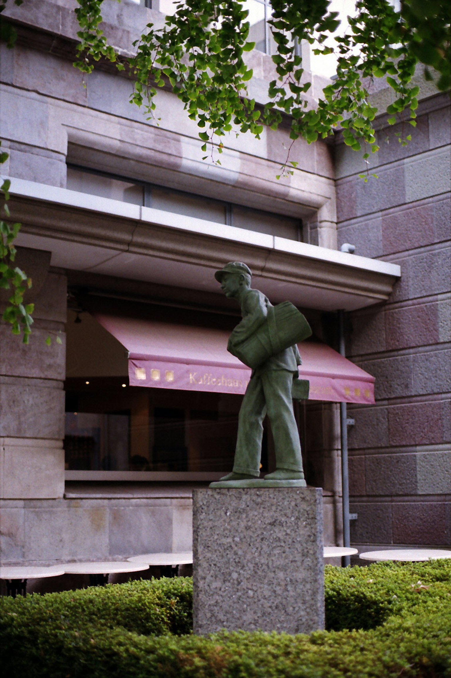 Scultura verde di un uomo con una borsa vicino all'ingresso di un edificio