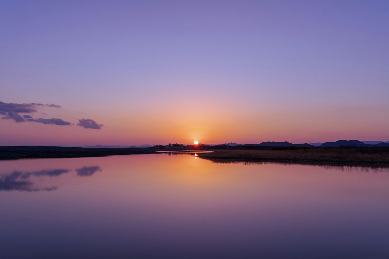 Coucher de soleil tranquille se reflétant sur l'eau calme avec un ciel violet