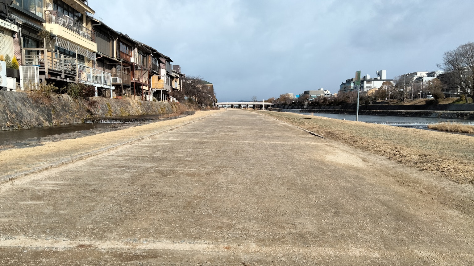Sentiero pavimentato lungo un fiume con edifici su entrambi i lati