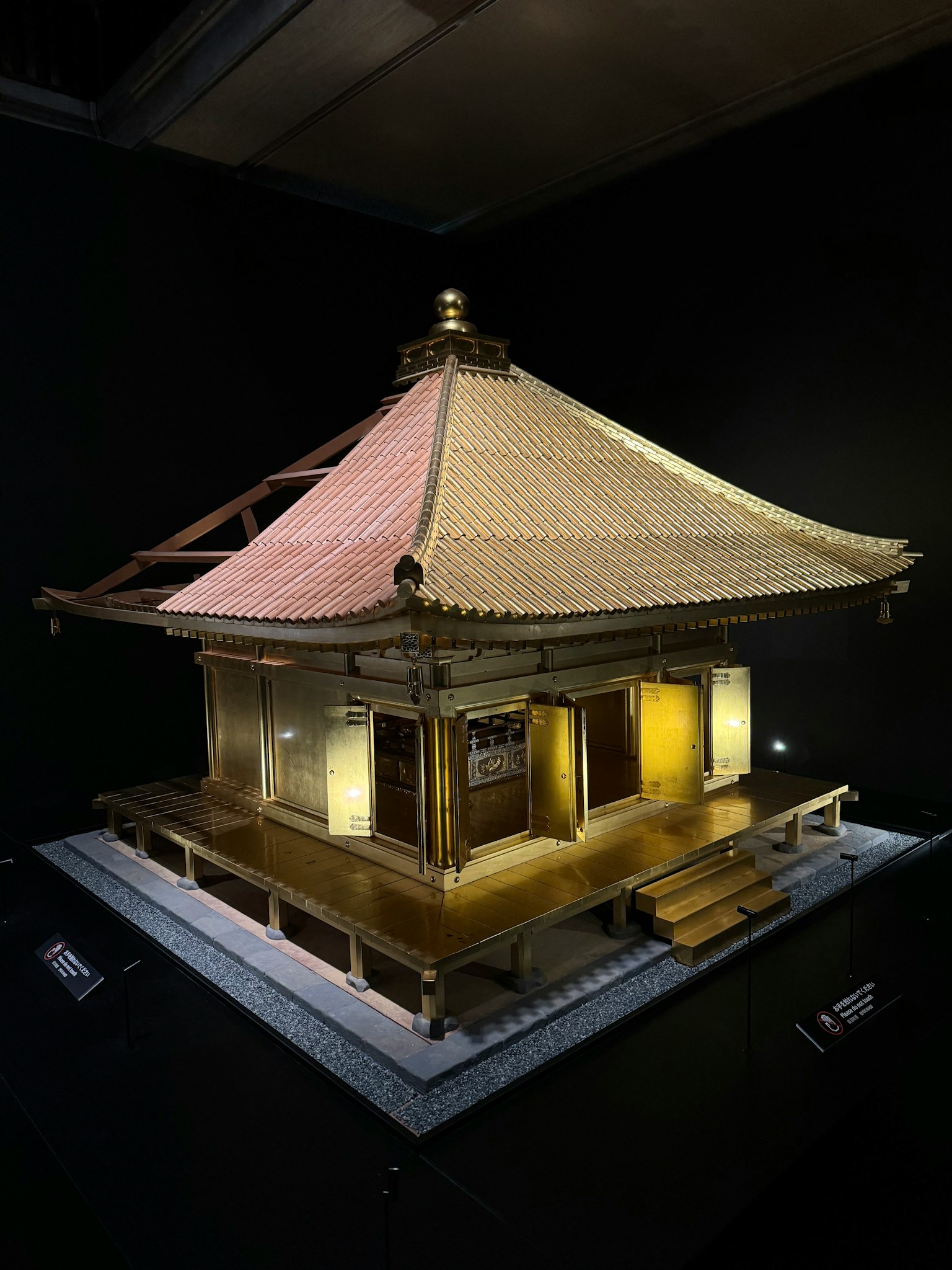 Modelo de un edificio japonés tradicional con un techo dorado parte de una exposición de arte