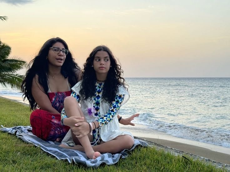 Two women sitting together on grass by the seaside