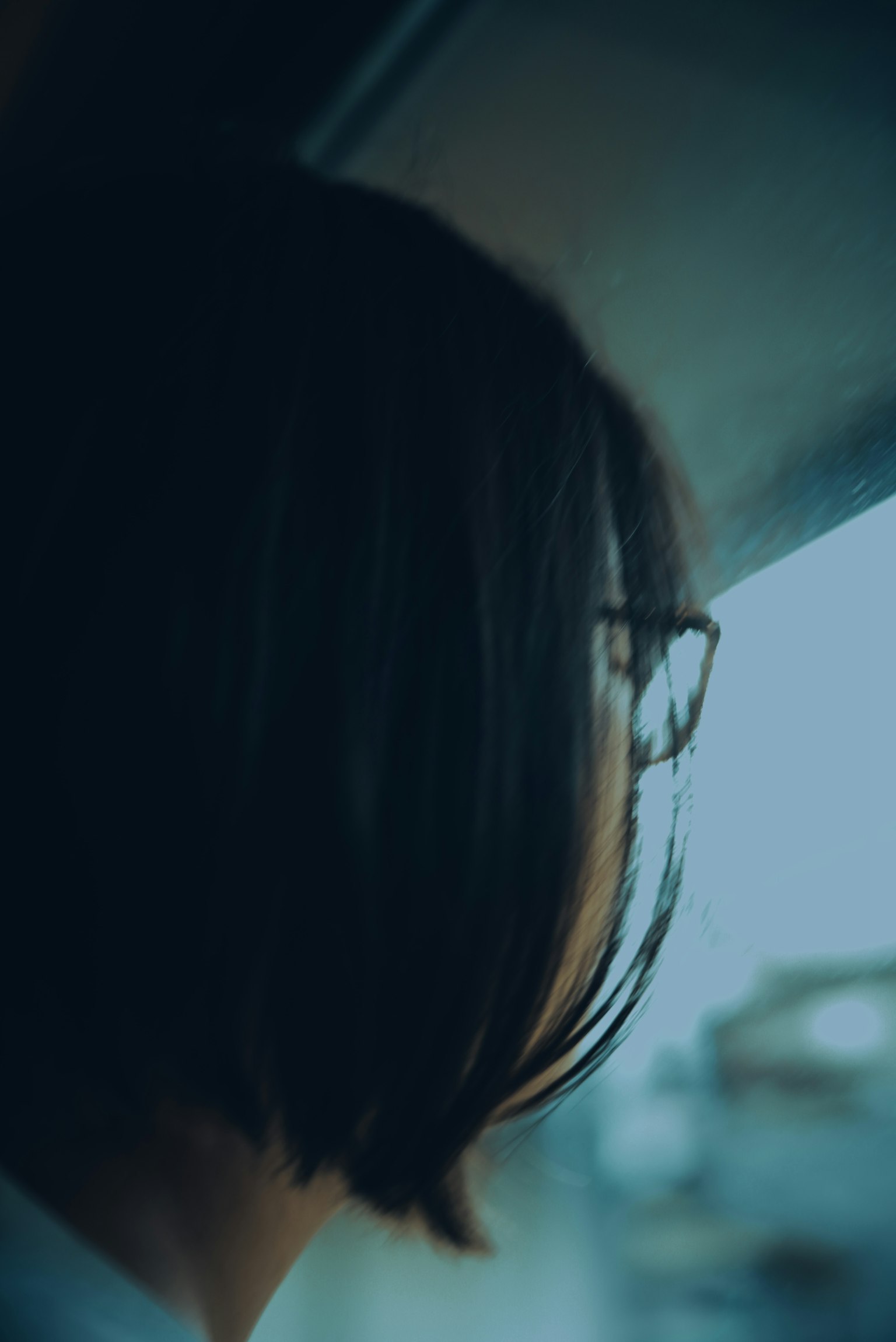 Back view of a woman wearing glasses looking out the window