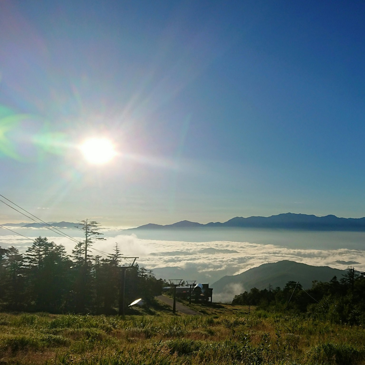 Panoramablick auf die Sonne, die über einem Wolkenmeer mit Bergen im Hintergrund scheint