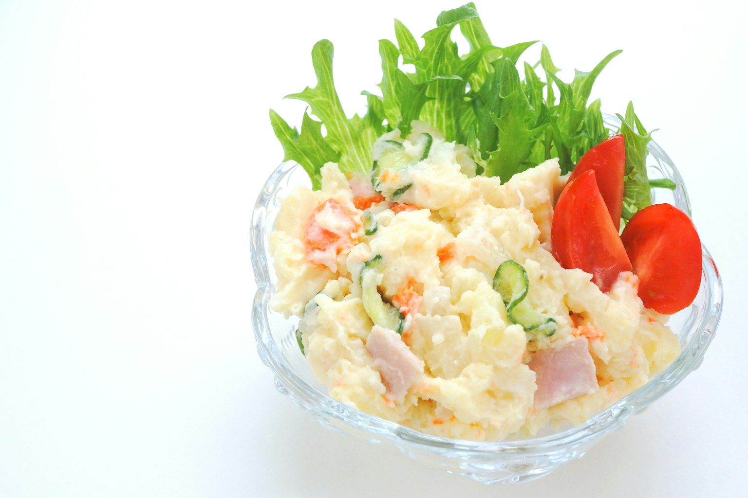 Salade de pommes de terre servie dans un bol en cristal avec des légumes frais et des tomates cerises