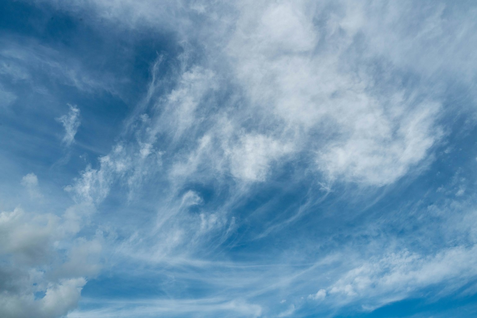 Expansive blue sky with wispy white clouds