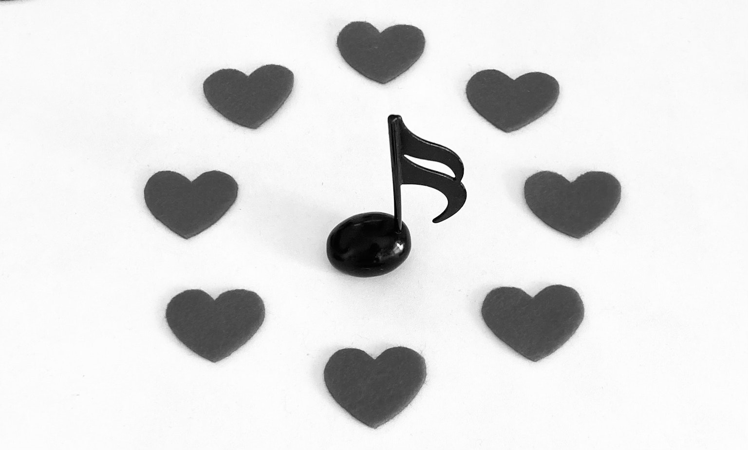 Una nota musical negra rodeada de corazones en una disposición circular