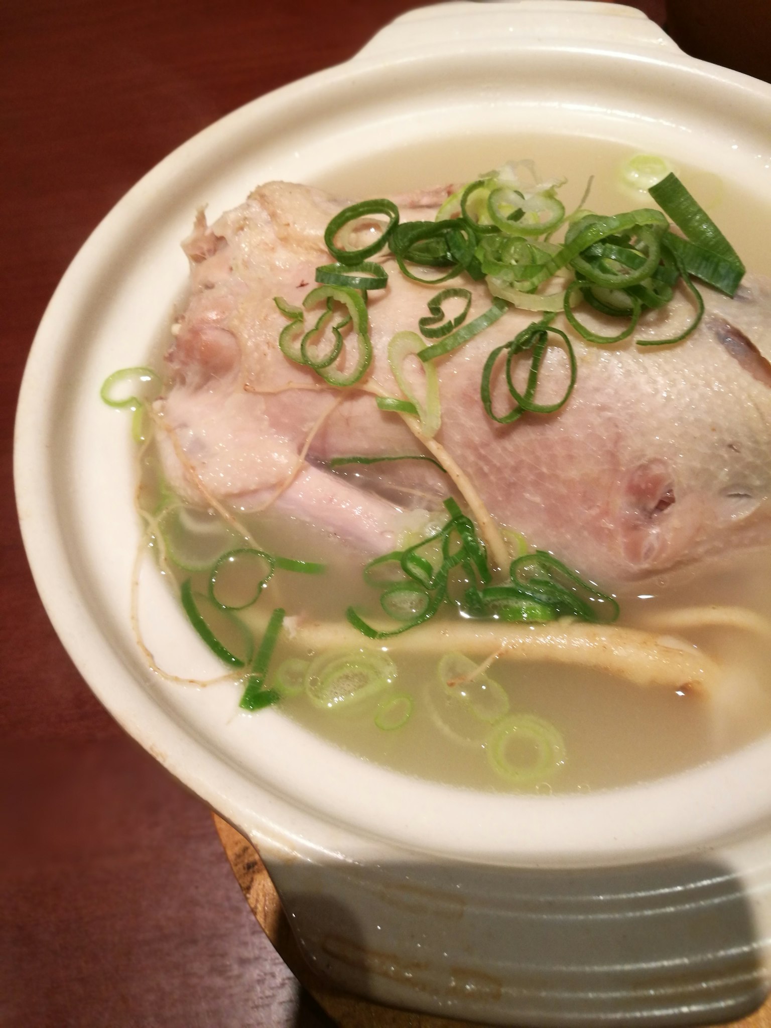 白色碗中盛放鱼头和高汤，上面撒有青葱