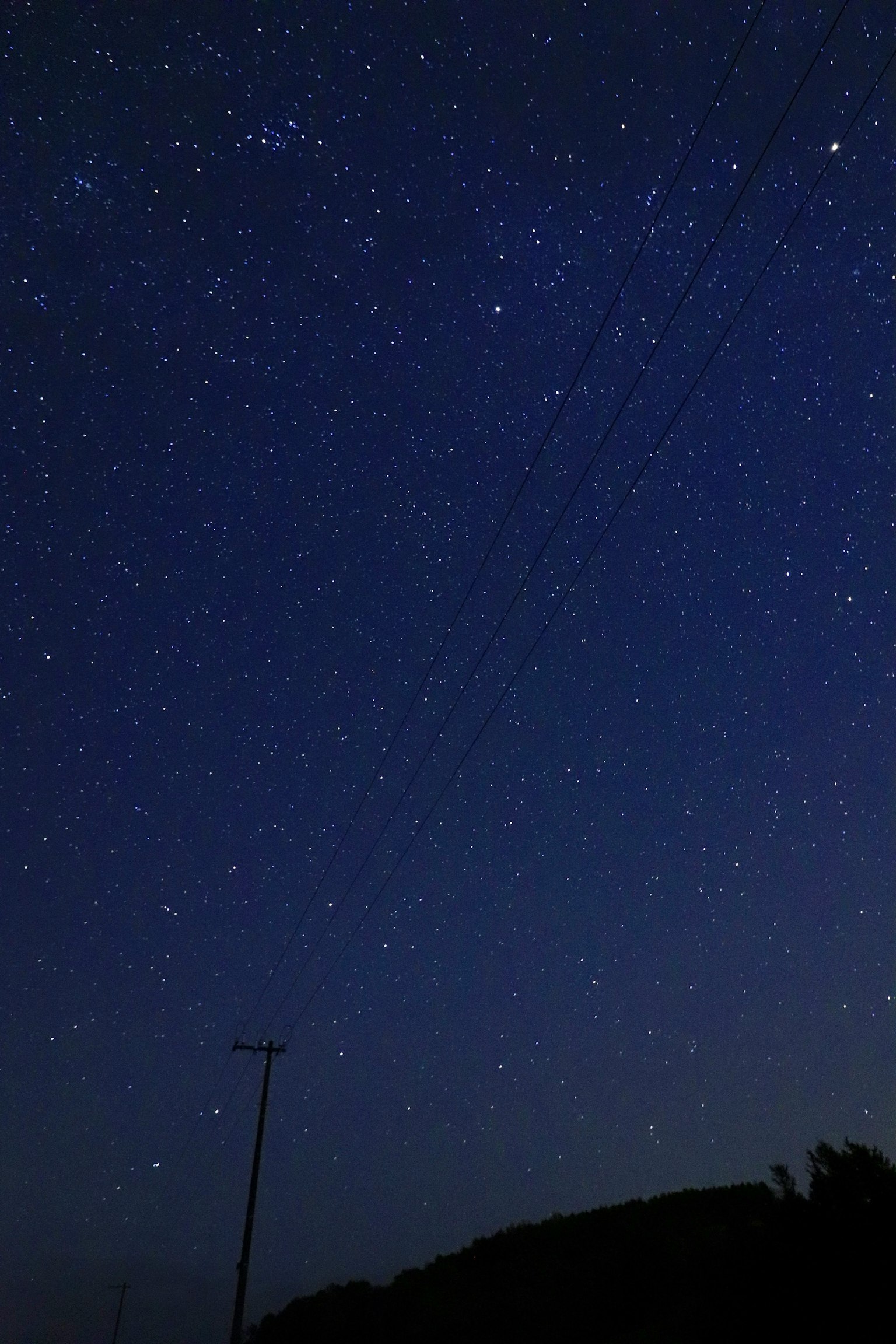 星光璀璨的夜空與黑暗的山丘輪廓