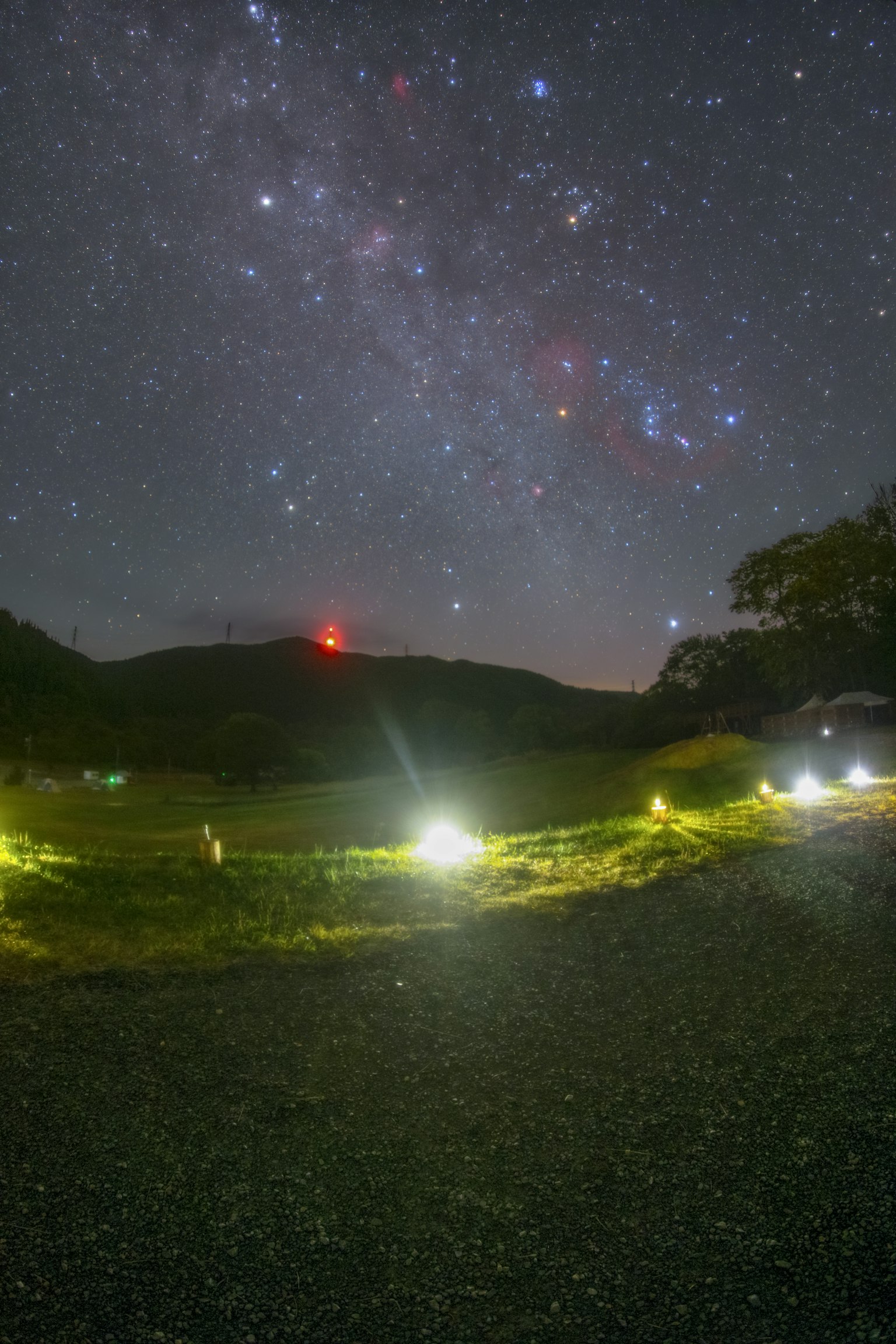 Paisaje nocturno con cielo estrellado y campo iluminado