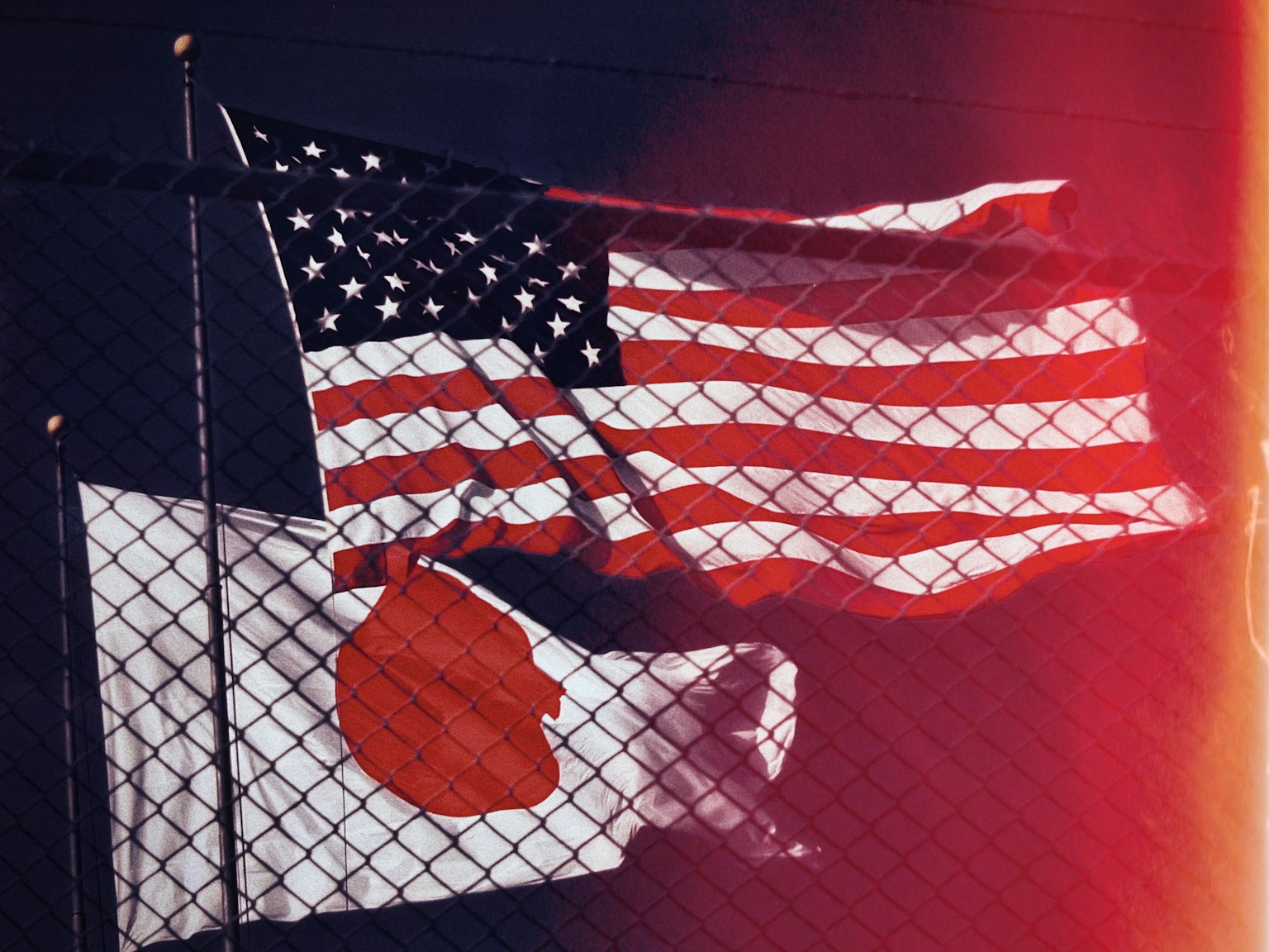 American and Japanese flags waving behind a fence