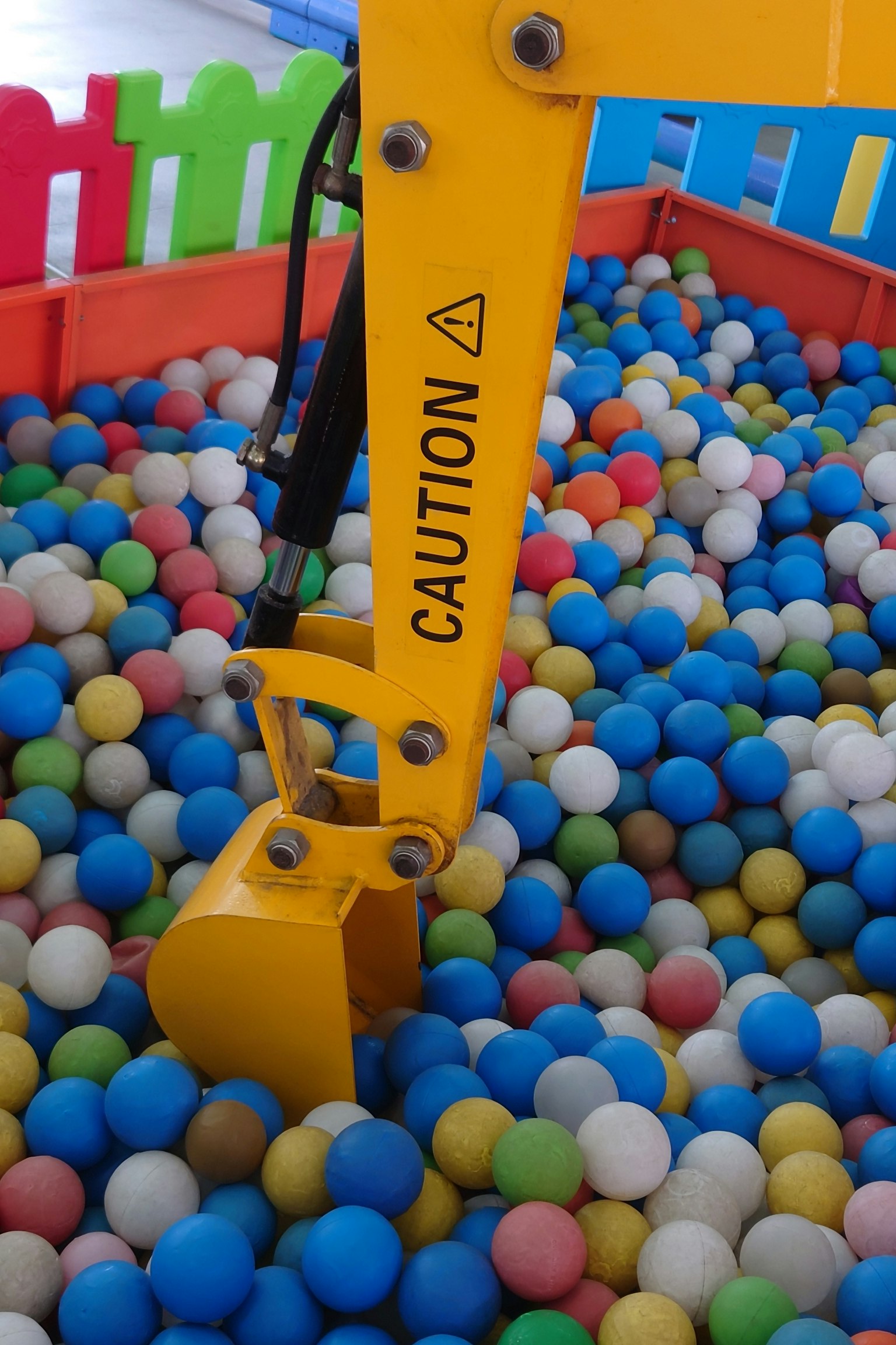 Bras de grue jaune sur une fosse à balles colorées