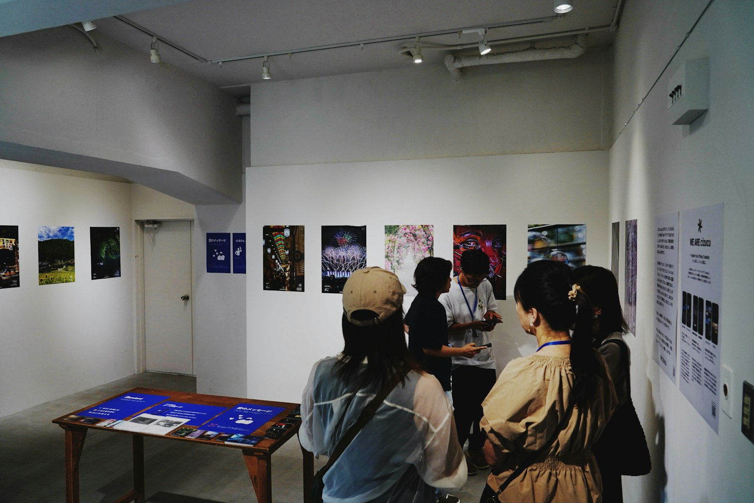 Persone che osservano opere d'arte in una galleria con manifesti esposti