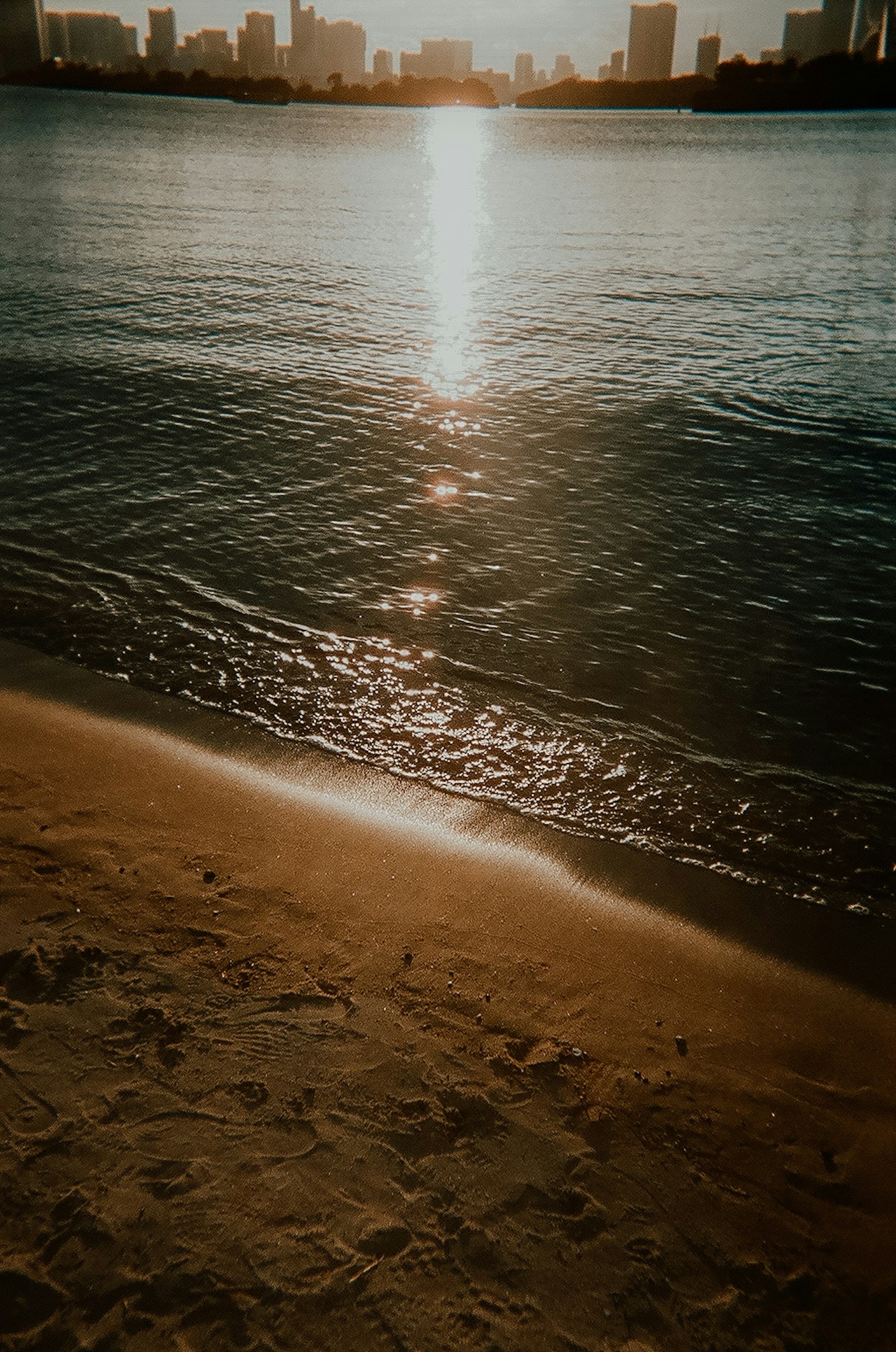 Scena di spiaggia con il tramonto che si riflette sulla superficie dell'acqua