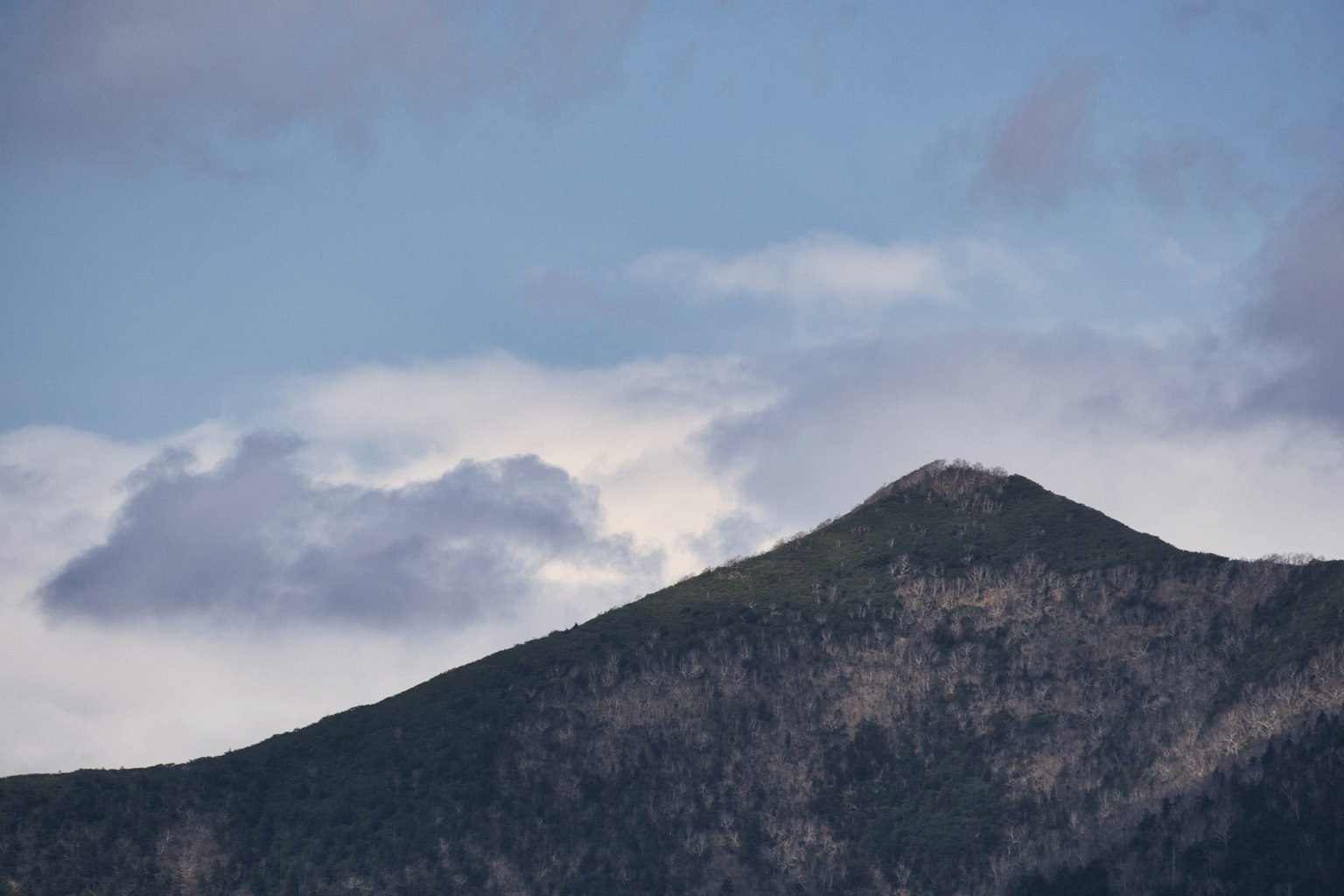 Sommet de montagne sous un ciel bleu avec des nuages